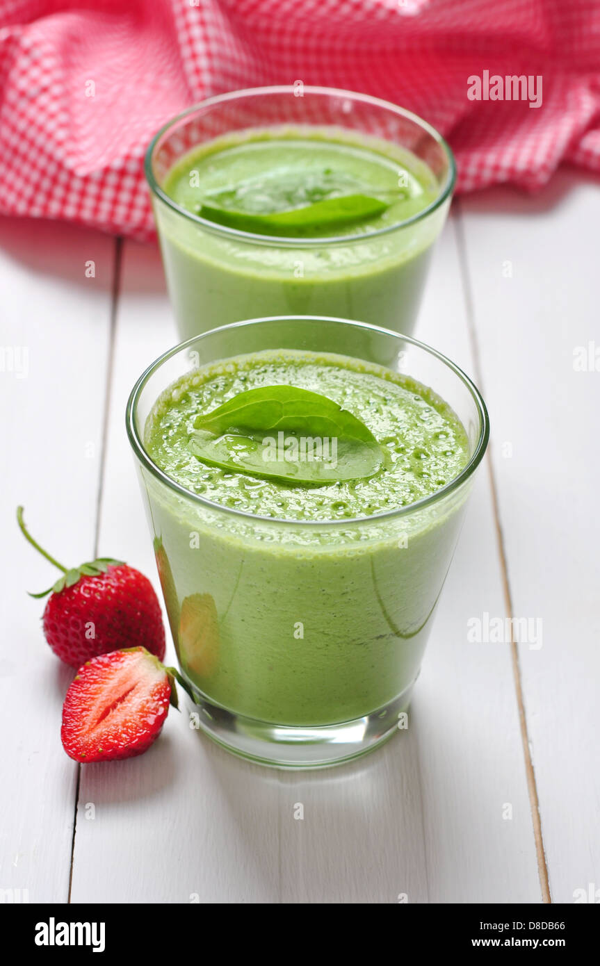 Spinat-Smoothies im Glas serviert mit Erdbeeren auf einem hölzernen Hintergrund Stockfoto