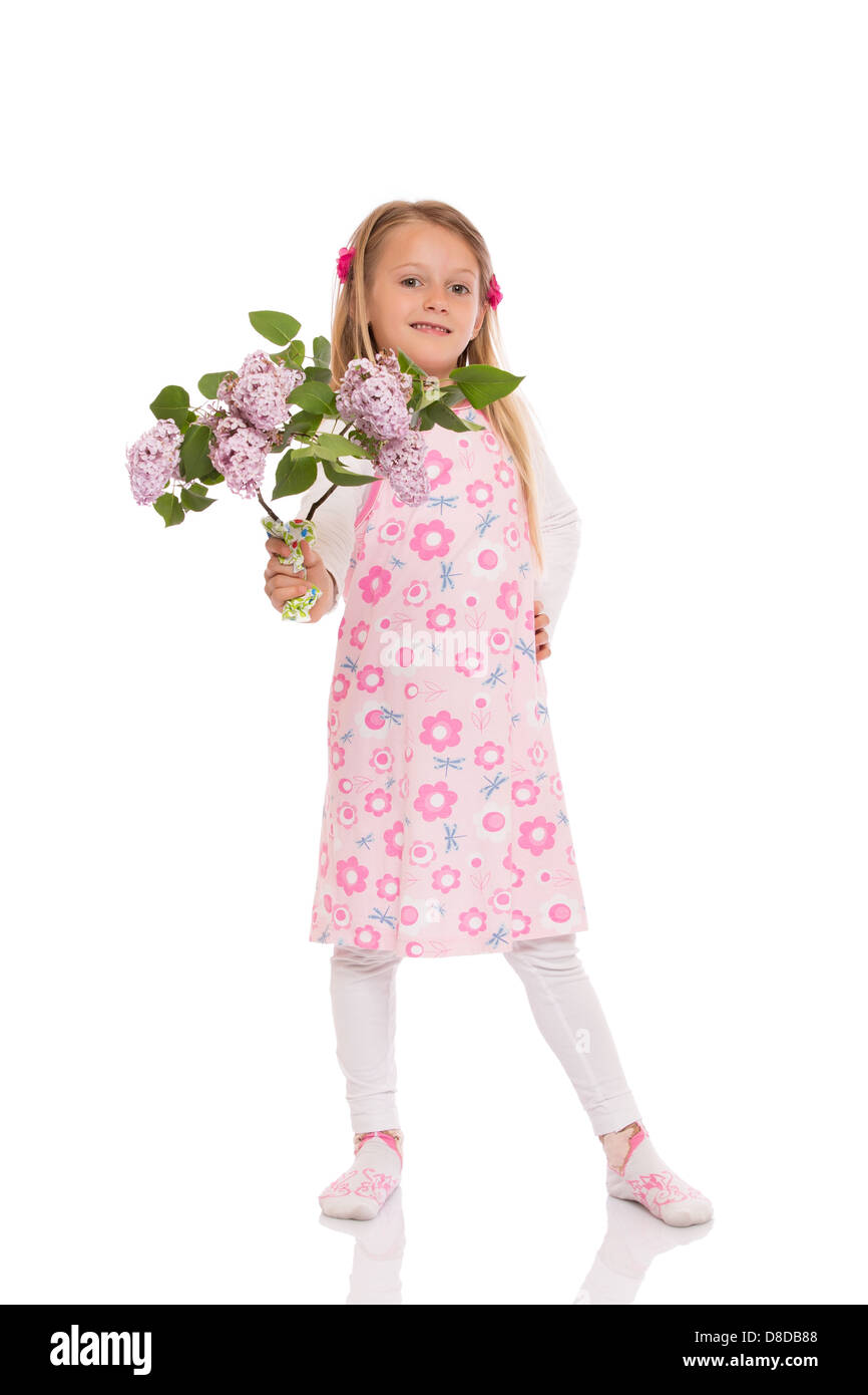 Kleines Mädchen Lächeln mit langen Haaren tragen Sommerkleid stehen und halten lila Blumen. Isoliert auf weißem Hintergrund. Stockfoto
