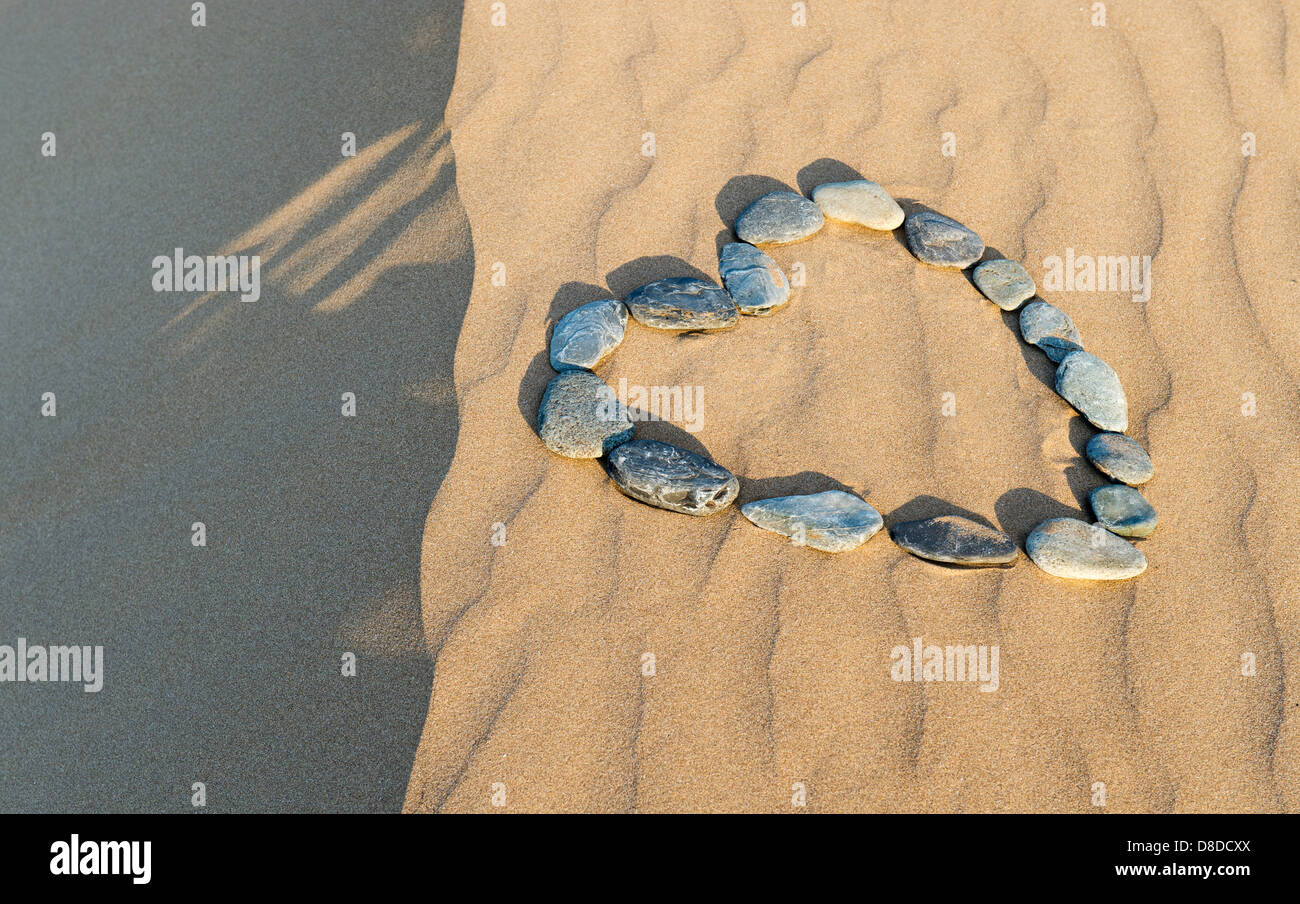 Herz-Form-Kieselsteine auf einer Sanddüne Stockfoto