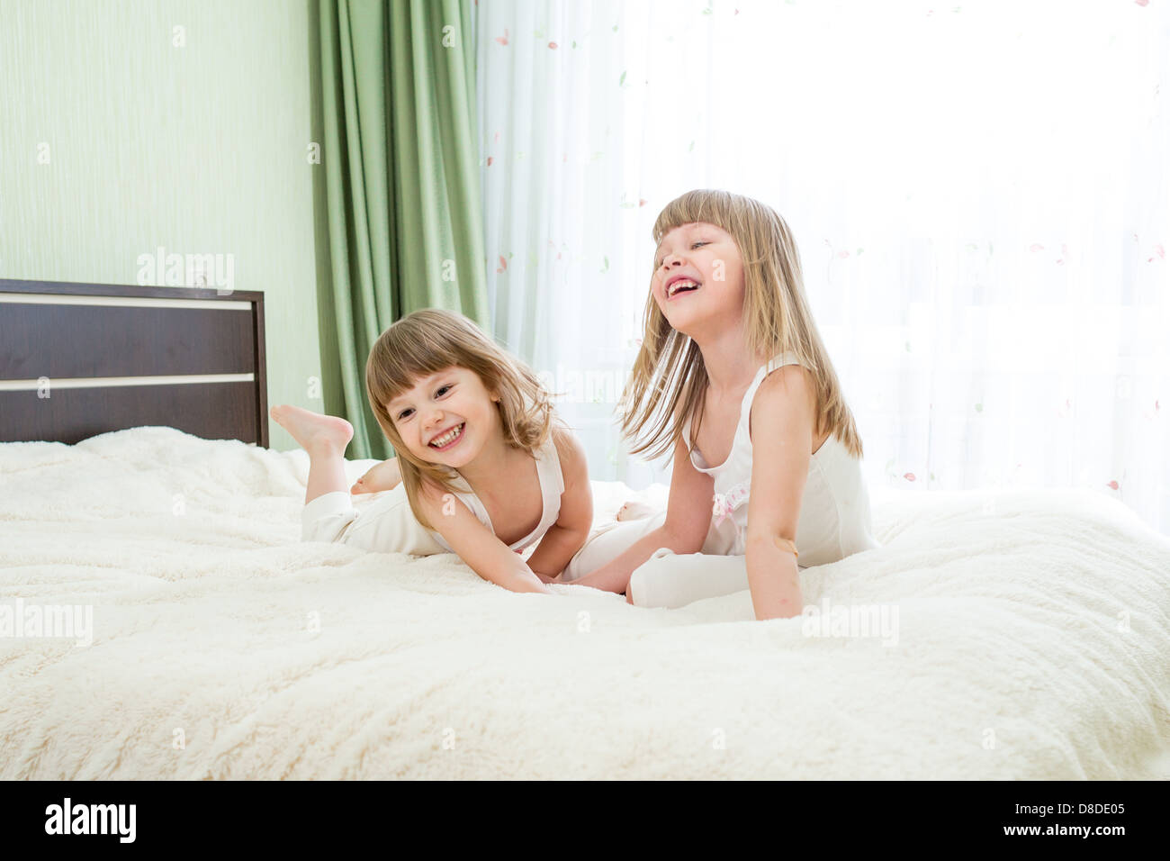 Zwei kleine Mädchen auf dem Bett liegend Stockfoto