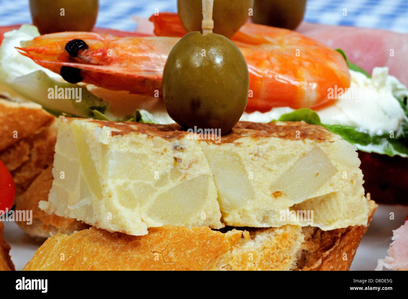 Spanische Tapas-Auswahl, mit spanische Tortilla garniert mit grünen Oliven und serviert auf knusprigem Brot im Vordergrund, Spanien. Stockfoto