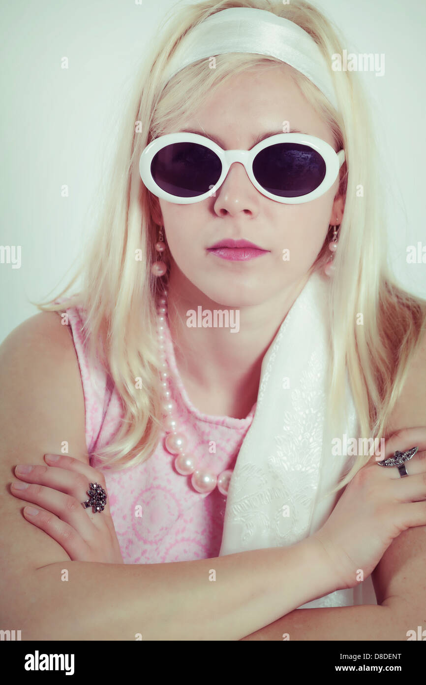 ein 60er Jahre Mädchen mit Sonnenbrille und rosa Kleid Stockfoto