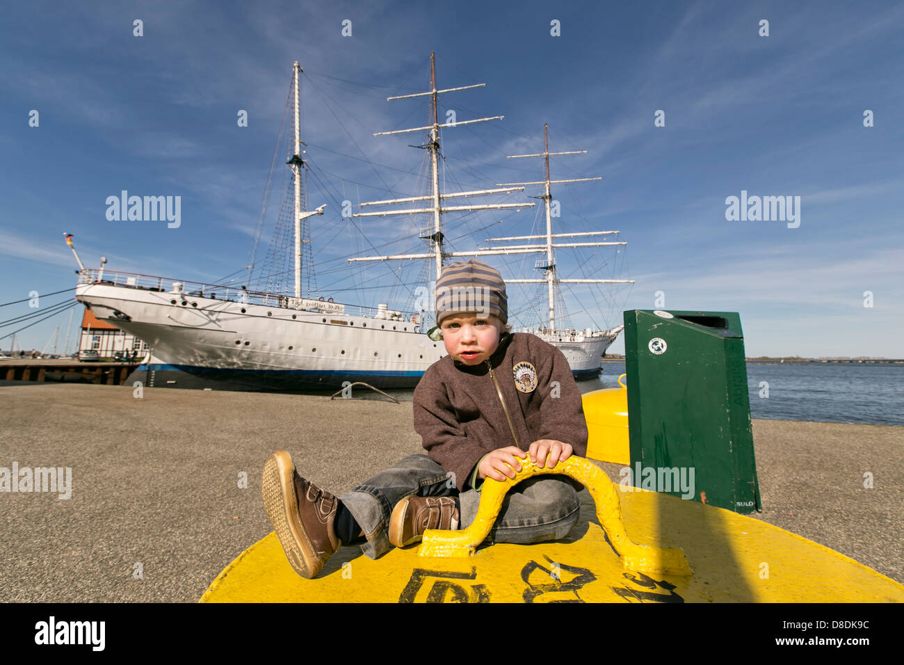Junge, 2 Jahre vor einem Rahsegler Schiff in einem Hafen Stockfoto