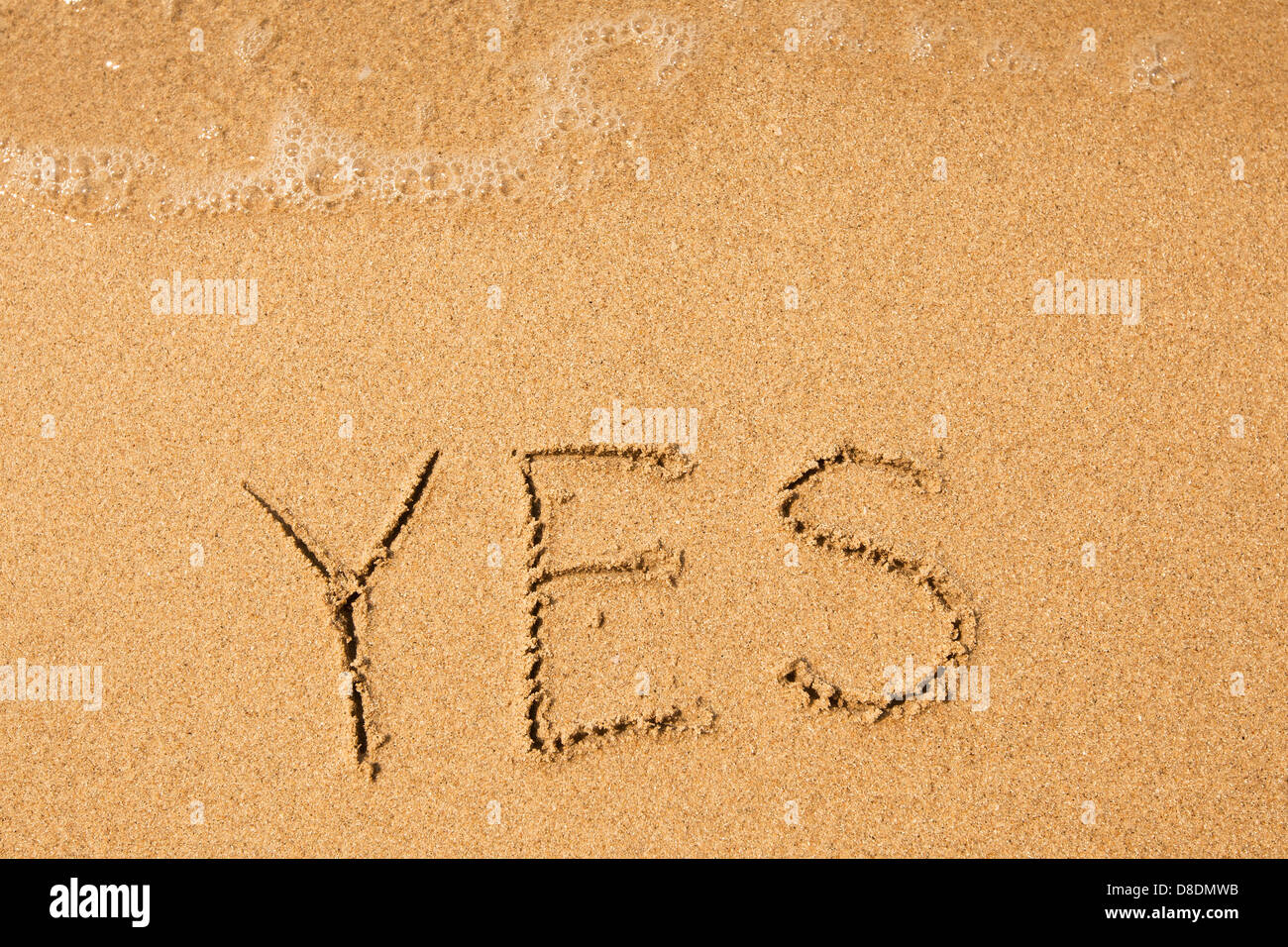 Ja - geschrieben im Sand am Strand Textur, weiche Welle des Meeres Stockfoto