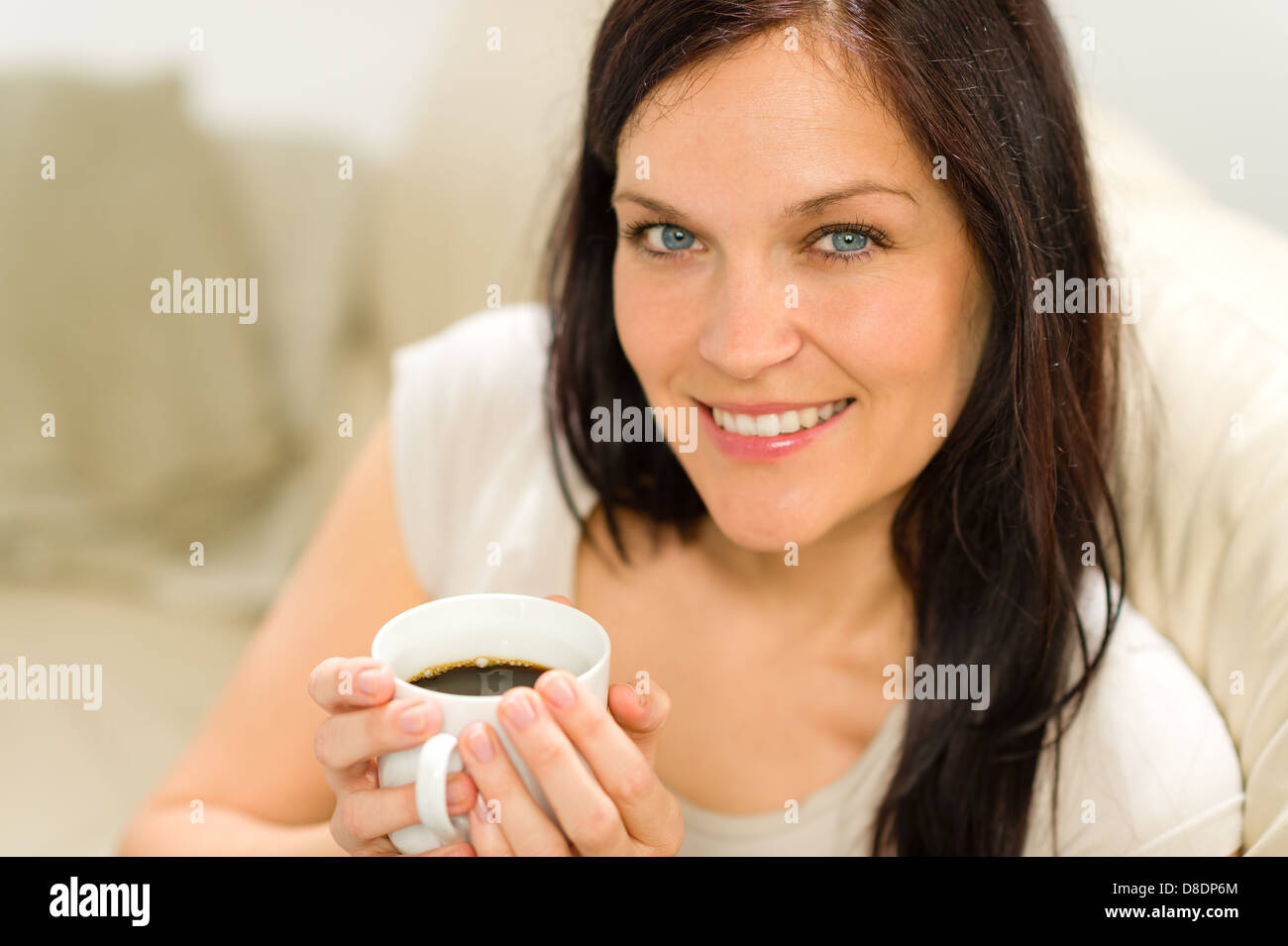 Lächelnd zufrieden Frau hält Tasse Espresso in gemütlicher Umgebung Stockfoto