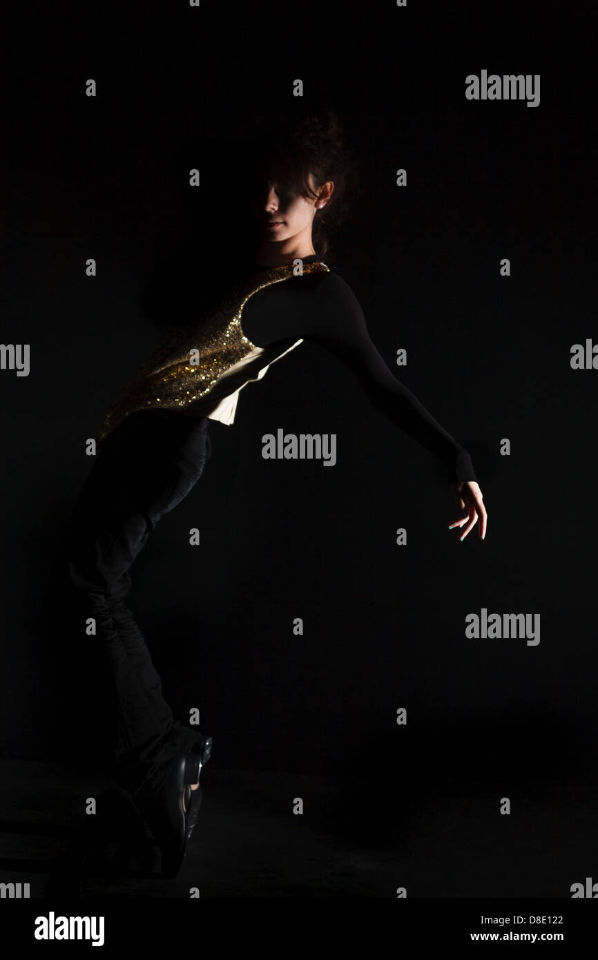 eine Tap-Tänzerin mit einem goldenen Weste, schwarze Spitze, schwarze Jeans, Low Key Beleuchtung Stockfoto