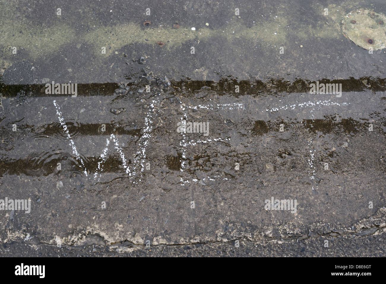 Das Wort nassen geschrieben in weißen Farbe auf Beton bei Nässe regnerisch. Stockfoto