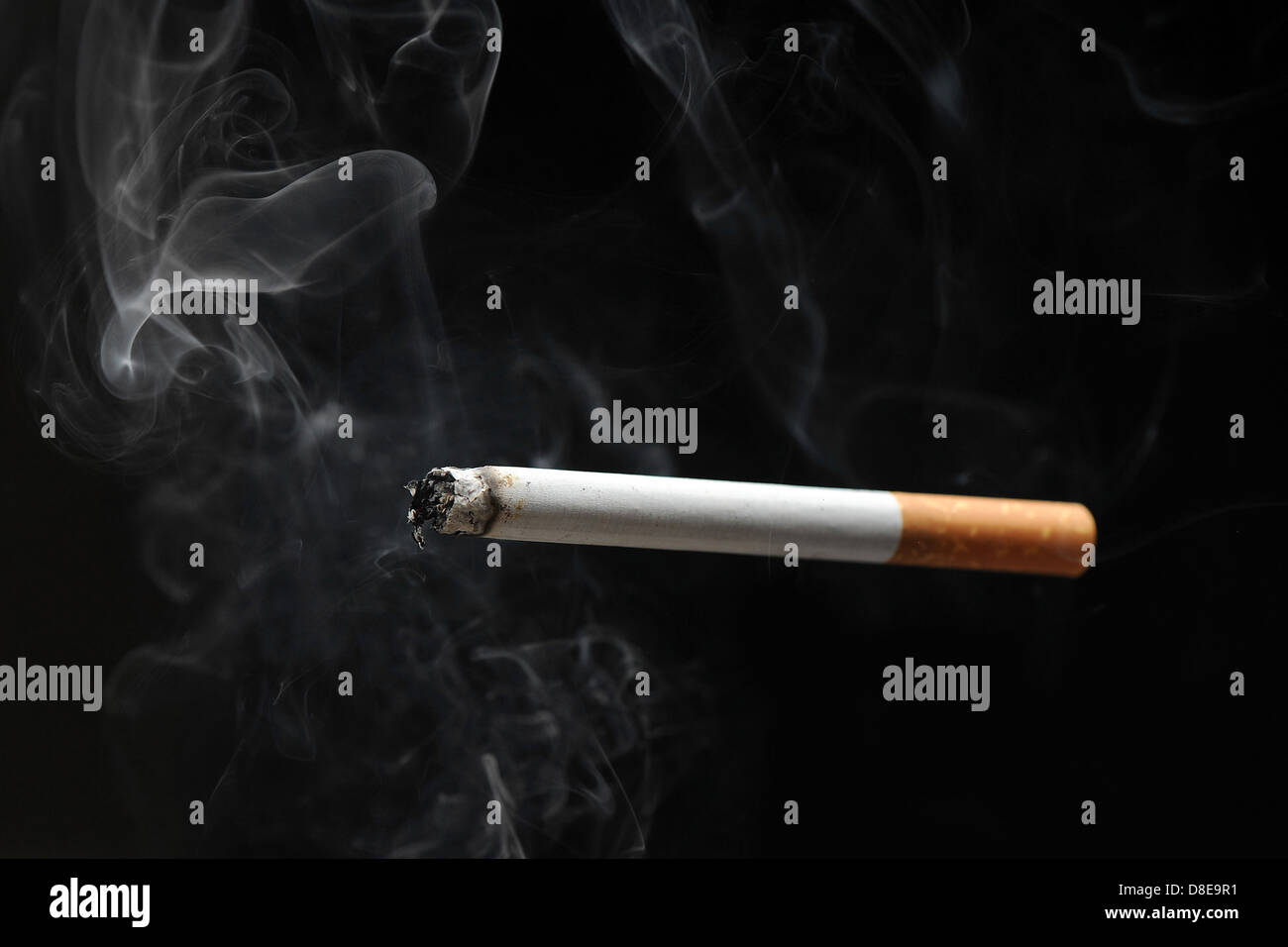 Eine brennende Zigarette Rauch vor einem schwarzen Hintergrund. Stockfoto