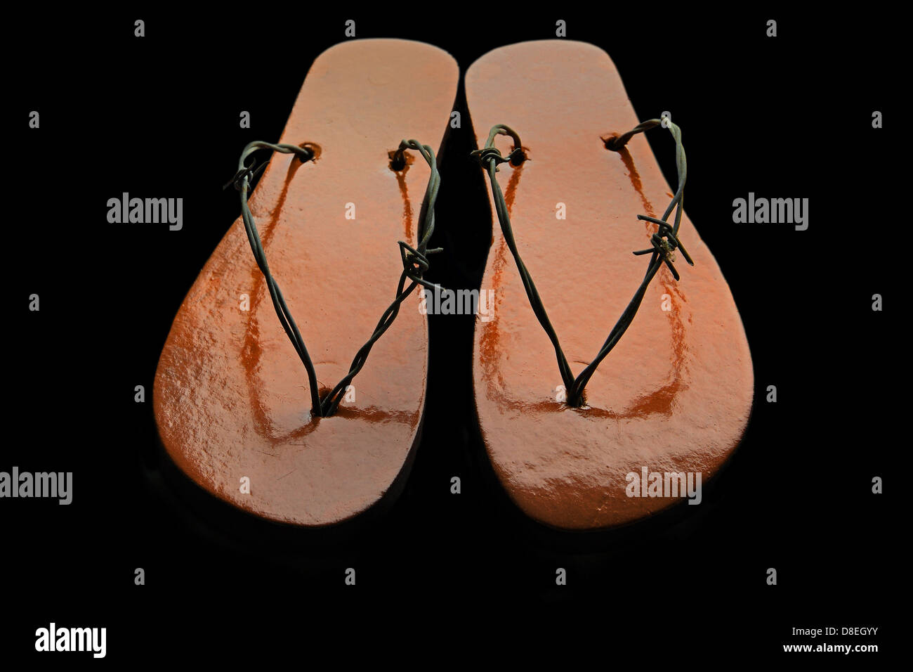 Orange Stacheldraht Flip-flops auf dunklem Hintergrund. Zurückhaltend Stockfoto