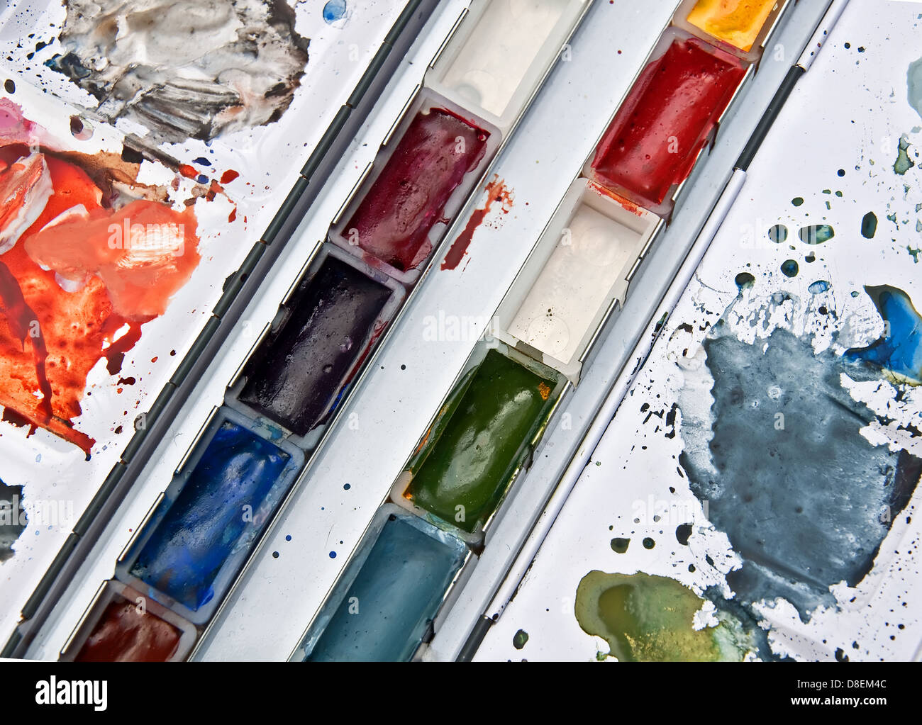 Dies ist ein Tablett mit Aquarellfarben in Pfannen und gemischt auf einer Palette eines Künstlers Materialien und Werkzeuge. Stockfoto