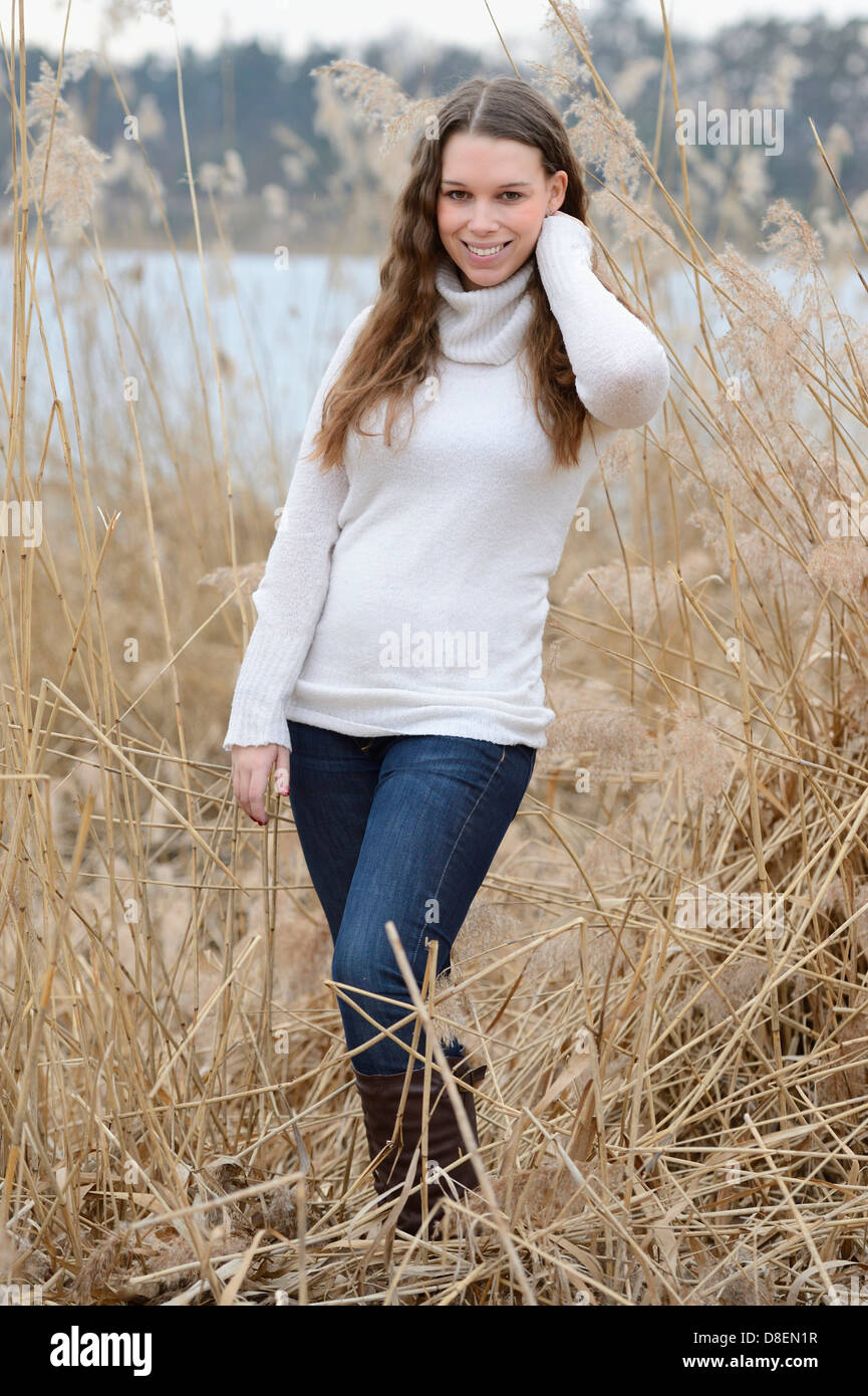 Lächelnde junge Frau in hohen Gräsern Stockfoto