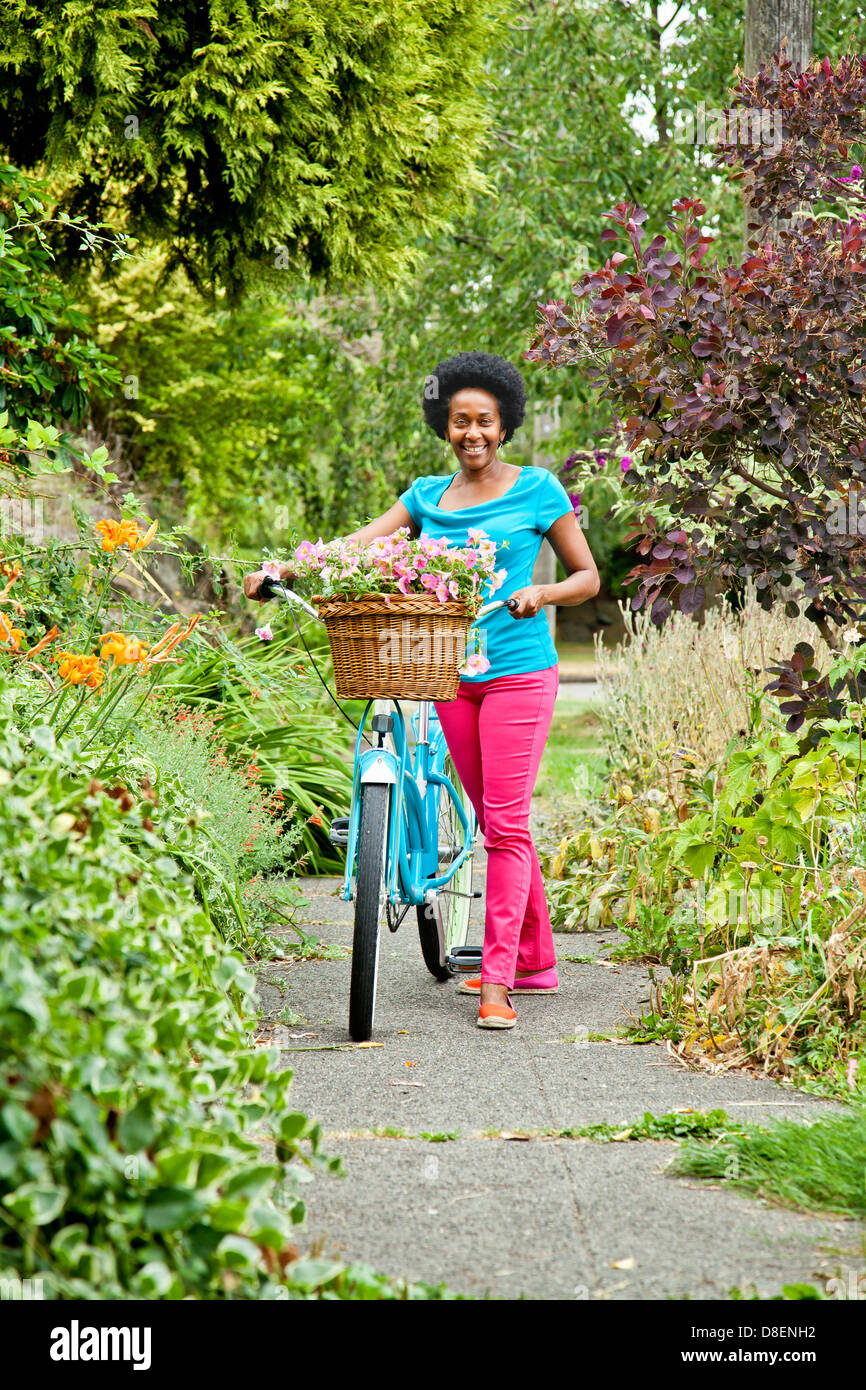Frau Reiten Retro-Fahrrad mit Blumenkorb Stockfoto