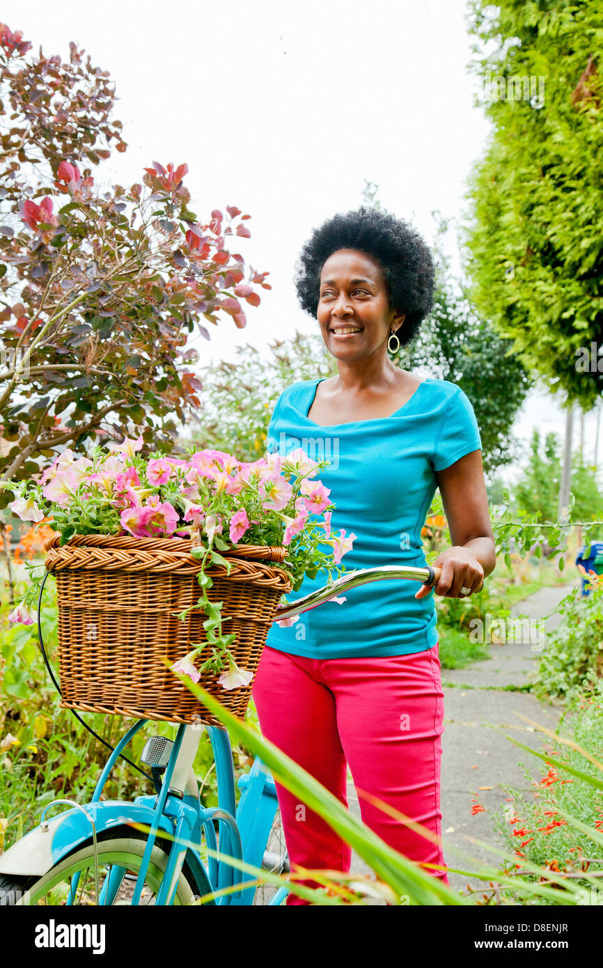 Frau Reiten Retro-Fahrrad mit Blumenkorb Stockfoto