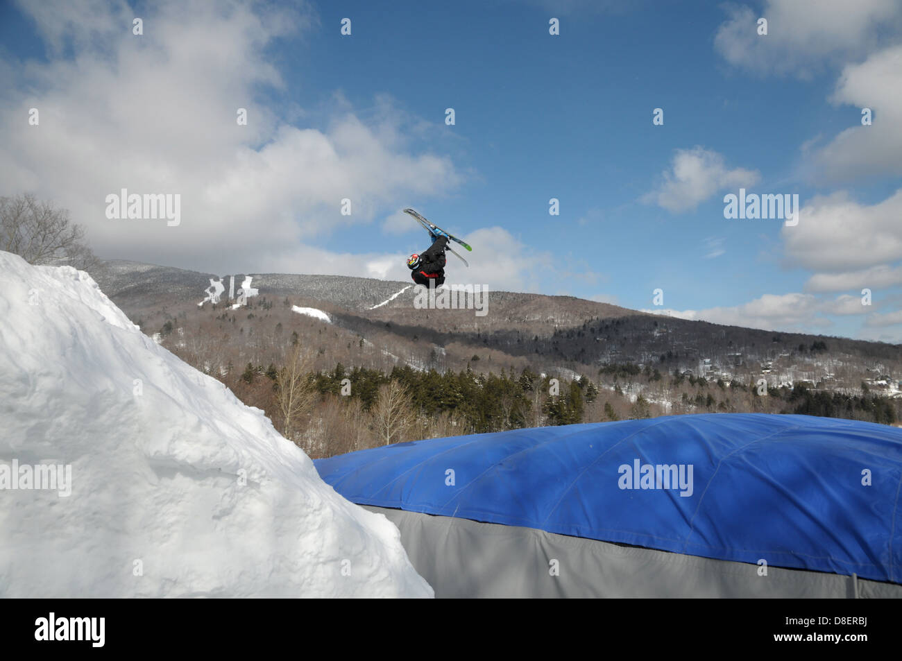 Ein extremer Skifahrer springt ein Sprung, wie er über den Boden auf einem Airbag im Sugarbush Resort in Warren, VT. Stockfoto