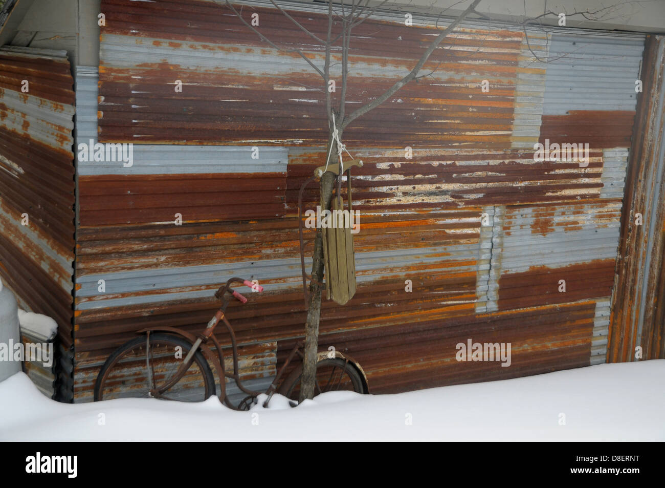 Einen Schlitten und ein altes Fahrrad sitzen Sie draußen einen Schuppen in Warren, Vermont. Stockfoto