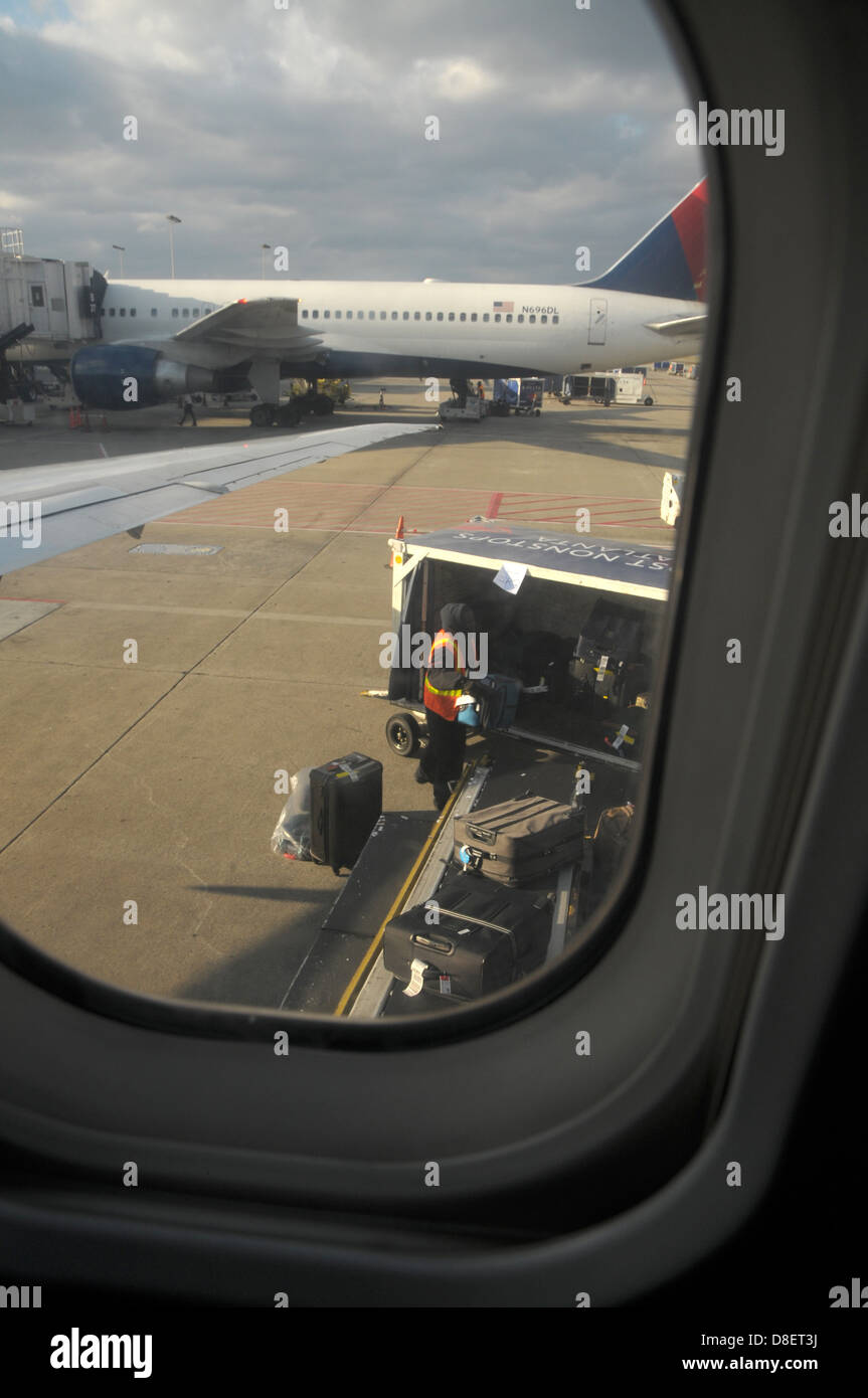Ein Gepäck-Handler für Delta Airlines stellt Gepäck auf einem Transportband in Vorbereitung für einen Flug. Stockfoto