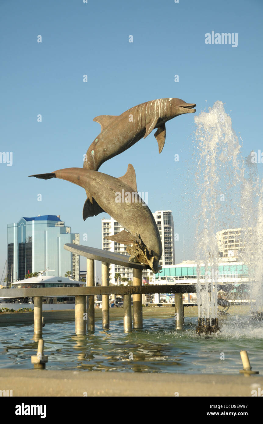 Delphin-Statuen zeigen sich in der Luft auf eine Wasserfontäne in Sarasota, FL direkt am Wasser. Stockfoto