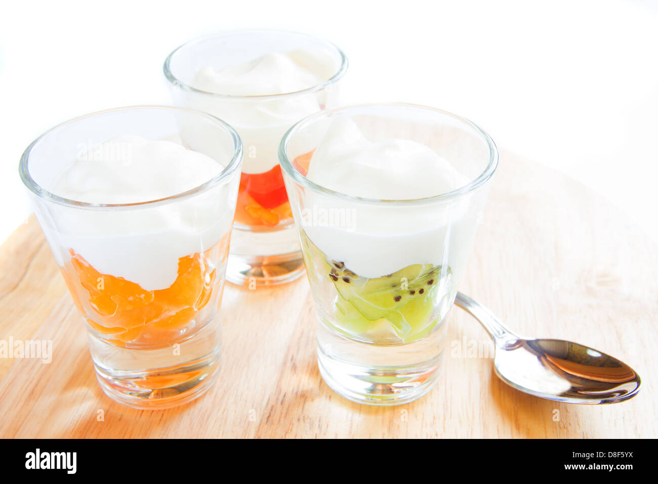Drei frischen Joghurt mit Früchten im Becherglas auf hölzernen Cutboard isoliert auf weißem Closeup, horizontal, Textfreiraum Stockfoto