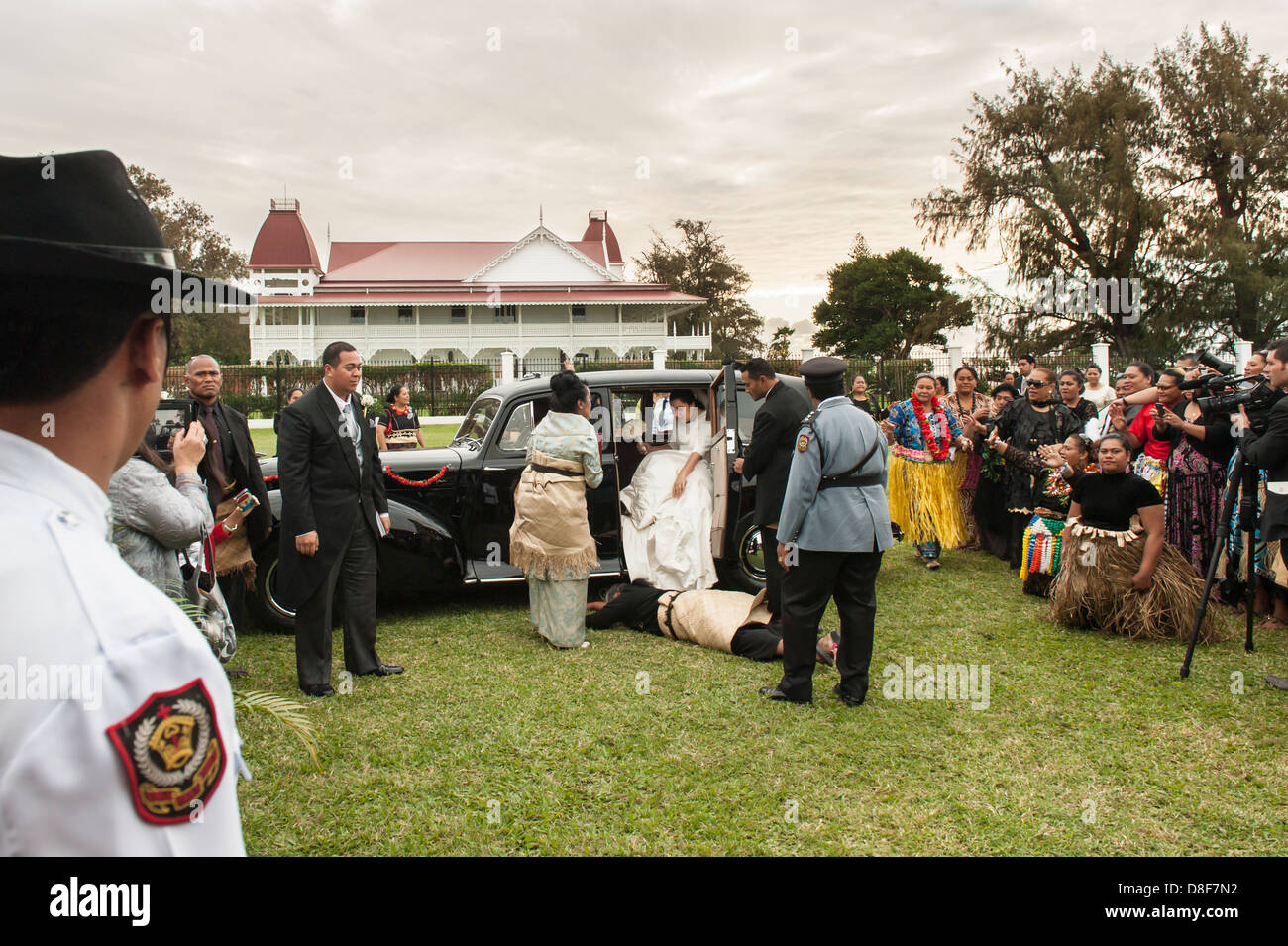 Eine Frau fällt auf den Boden mit Rücksicht auf die Braut, wie sie und der Kronprinz von Tonga auf ihrer Hochzeitsfeier ankommen Stockfoto