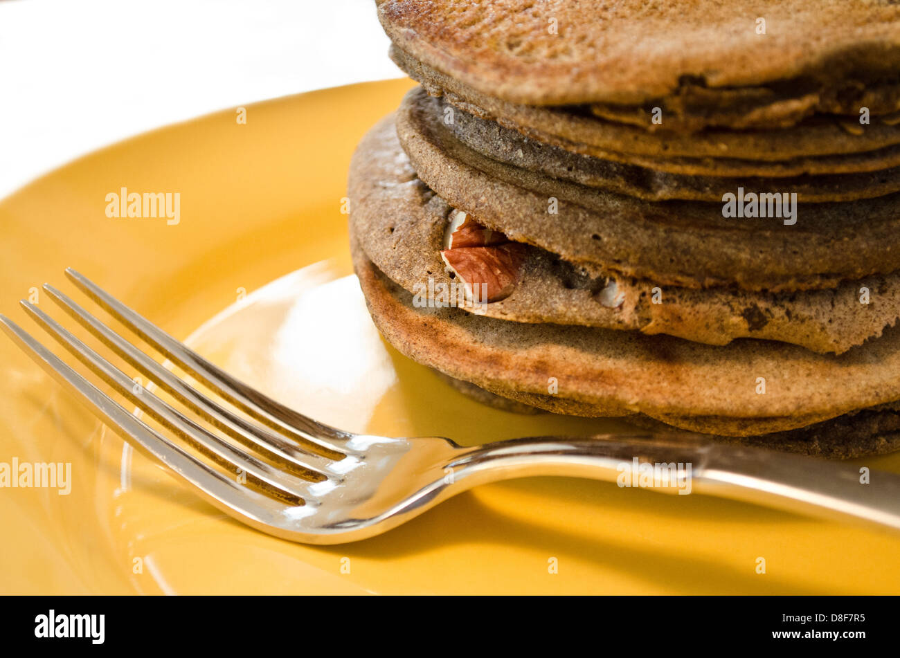 Stapel von Kürbis gewürzten Pekannüssen auf einem Teller zum Frühstück. Nahaufnahme von Flapjacks auf pflanzlicher Basis auf einer gelben Platte. Stockfoto