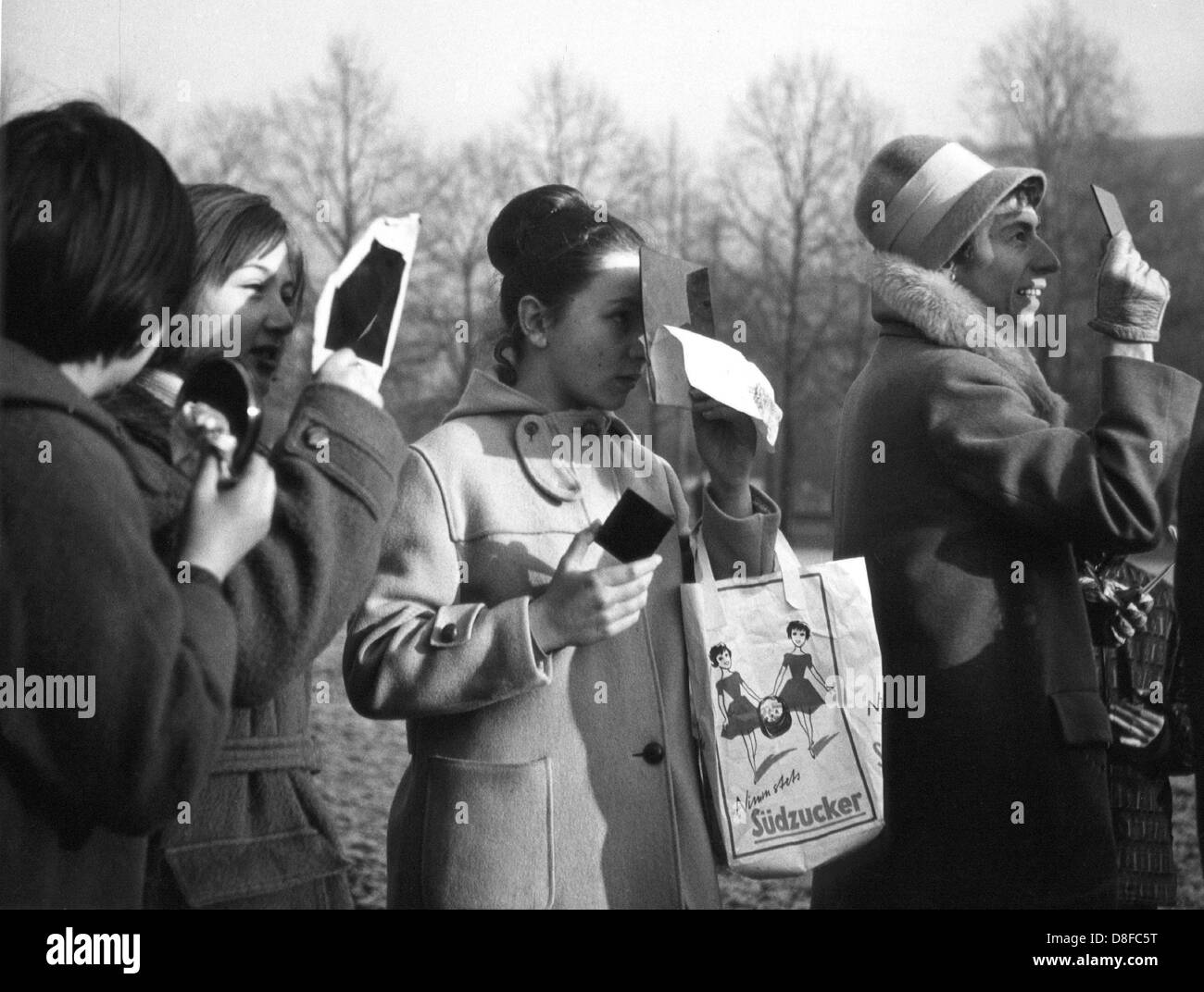 Schülerinnen und Schüler und ihre Lehrer aus München sehen die Sonnenfinsternis durch getönten Gläser am 15. Februar 1961. Stockfoto