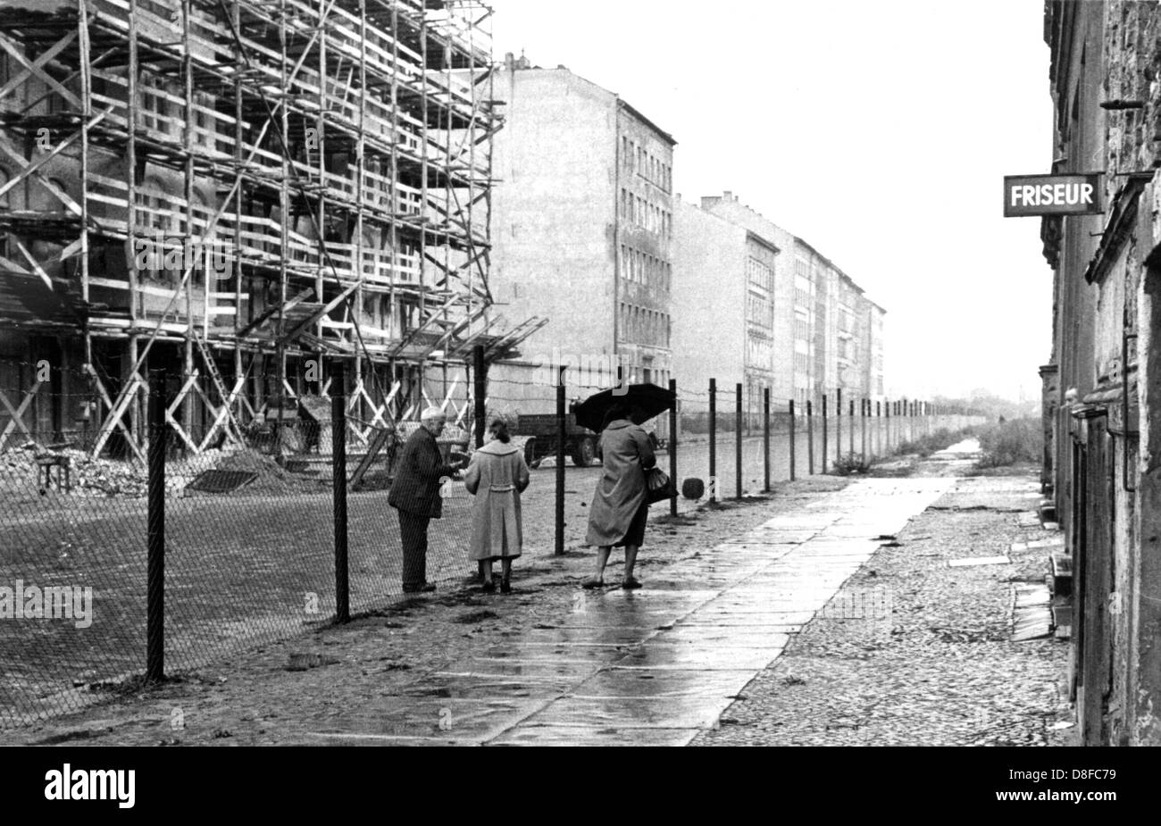 Ein Bürger der Ost-Berliner (l) fordert eine Frau von West Berlin (r), etwas aus einem Geschäft in einer geteilten Straße von Berlin am 17. August 1961. Betreut durch Streitkräfte der DDR, begann der Bau des Roadbarriers und der Bau der Berliner Mauer am 13. August 1961. Stockfoto