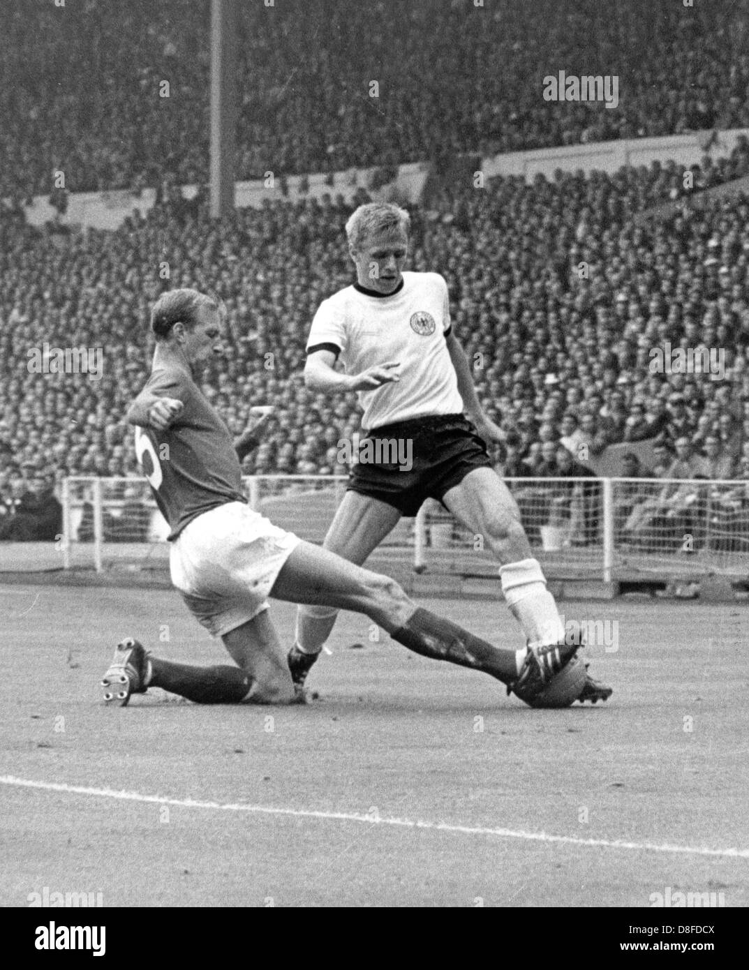 Englischen Verteidiger Jack Charlton (L) erstreckt sich sein Bein und hält den Ansatz der deutschen nach vorne Siegfried Held (R), der den Ball während 1966 WM-Endspiel Deutschland gegen England im Wembley Stadion in London, UK am 30. Juli 1966 hat. Deutschland verlor das WM-Finale in der Verlängerung mit einem Score von 2 bis 4 gegen England. Es war das erste WM-Titel für England. Stockfoto