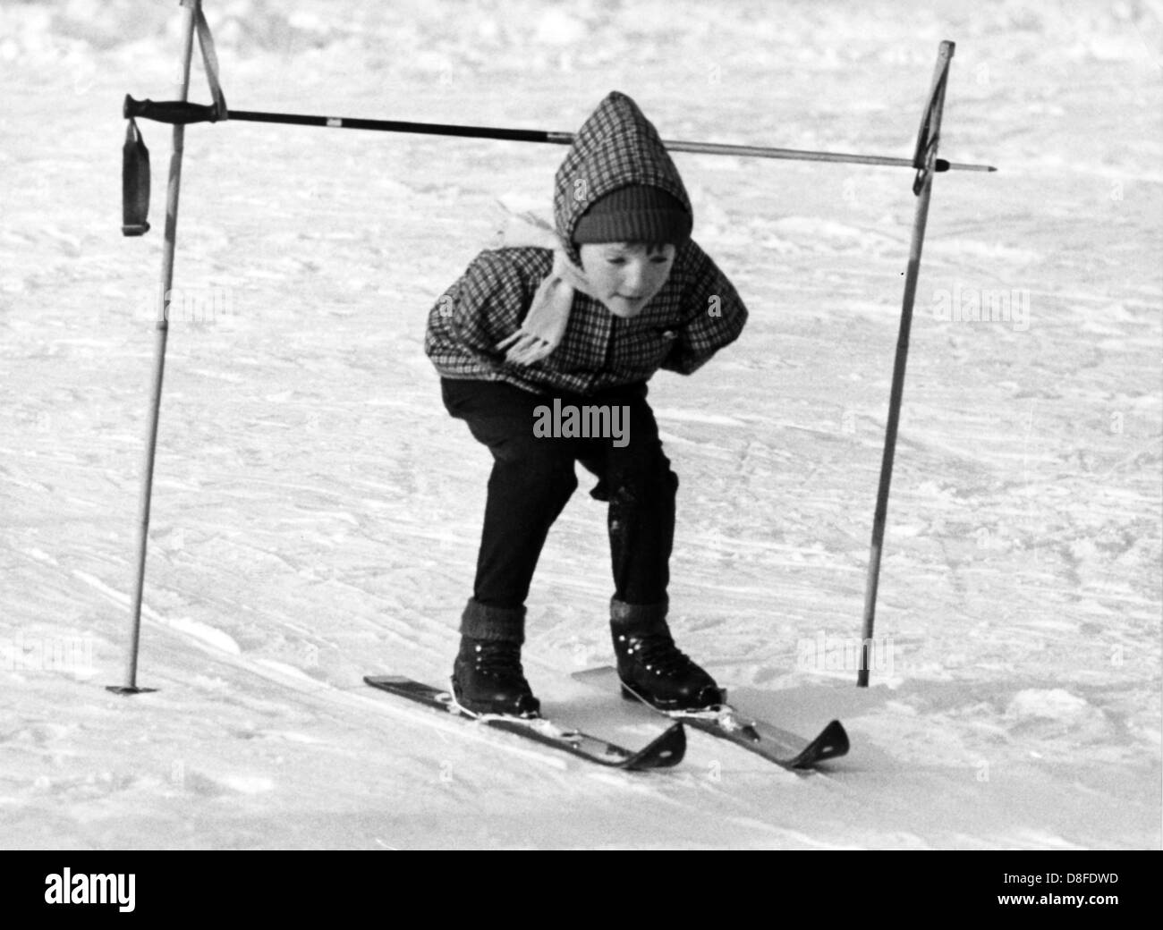 Ein behindertes Kind durchläuft einen Ziel-Build aus Skistöcke. 10 Contergan betroffenen Kinder aus Iserlohn (Deutschland), erfahren Sie, wie Skifahren im Januar 1968 im Bereich Sauerland in Deutschland. Die experimentelle Übung, die von Iserlohn Workers' Welfare Association in einem Kinderheim in der Nähe von Schürfelde (Meinertzhagen, Deutschland), durchgeführt wird zielt darauf ab, neue aktive Bewegungstherapien zu testen. Die Schulkinder im Alter werden von einem Physiotherapeuten und Skilehrer betreut. Stockfoto