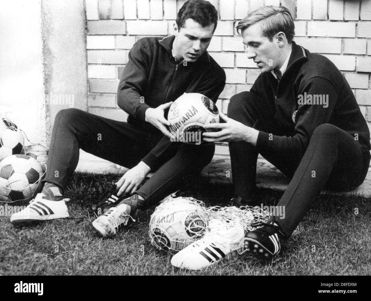 Deutsche Nationalspieler Franz Beckenbauer (l) und Günter Netzer (r) haben einen Blick auf neue Fußbälle während eines Trainingslagers am 9. November 1965. Stockfoto