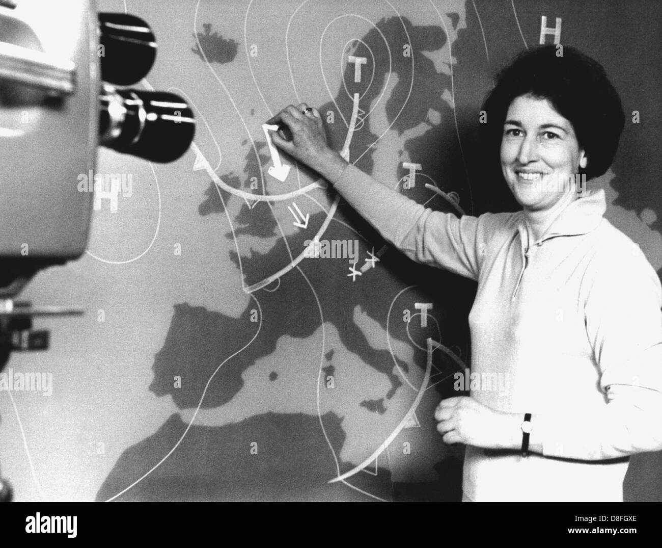 Meteorologe Dr. Karla Wege lächelt und verweist auf die Wetterkarte. Sie wird die Gruppe der acht männlichen Meteorologen am 5. Februar 1968 beitreten, als erste Frau, die durch gegenwärtige das Wetter jeden Abend im ZDF, der "zweiten deutschen Fernsehen", dreht wird als "Zweite deutsche Fernsehen übersetzt". Stockfoto
