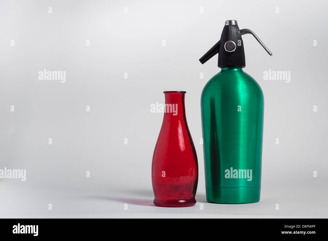 Stillleben mit Flasche roten und grünen Seltzer Siphon auf grauem Hintergrund Stockfoto