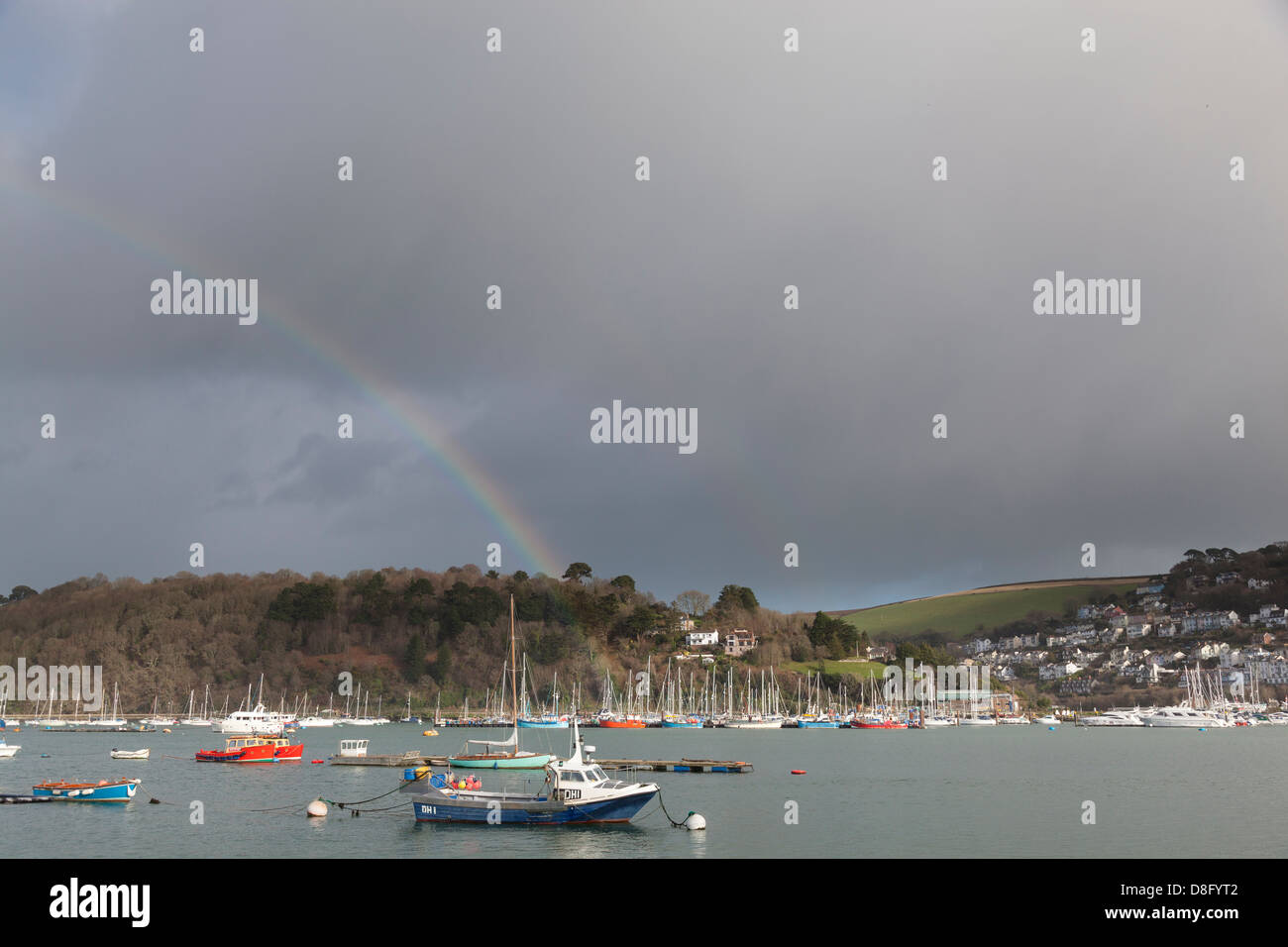 Regenbogen gegen einen dunklen Gewitterhimmel im Hafen von Dartmouth mit Kingsweir Marina gegenüber. Stockfoto