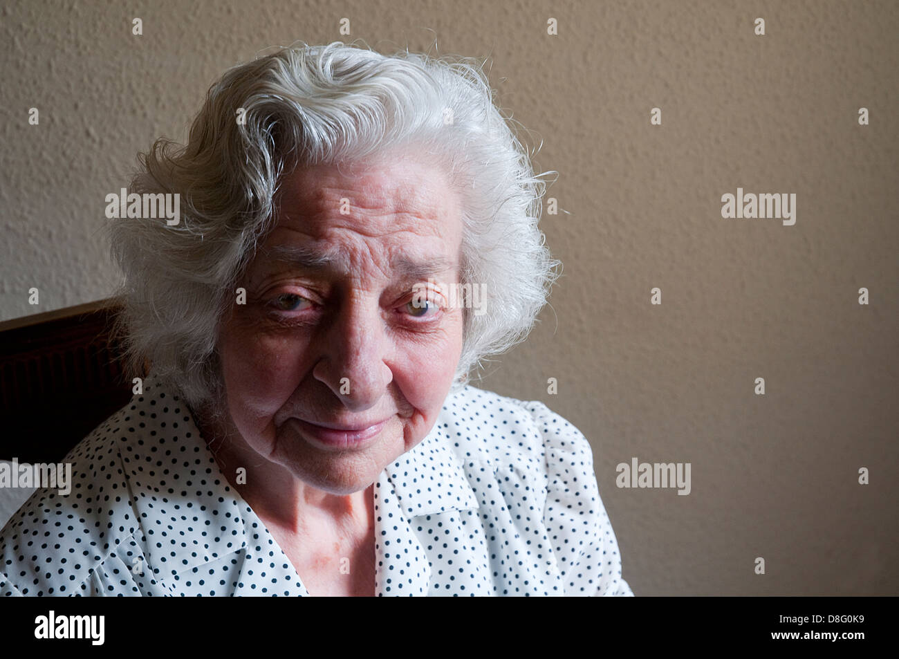 Porträt der älteren Frau zu Hause, lächelt und schaut in die Kamera. Stockfoto