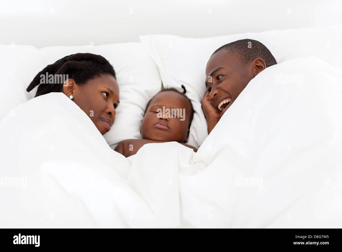 afrikanische amerikanische Brautpaar reden auf Bett mit Baby im mittleren schlafen Stockfoto