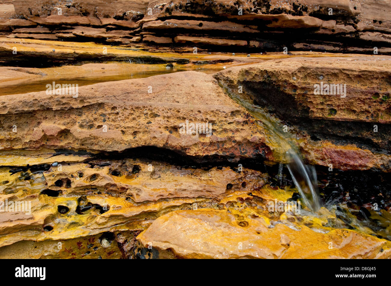 Wasser läuft unten aus natürlichen Wasserbecken im Felsen Stockfoto