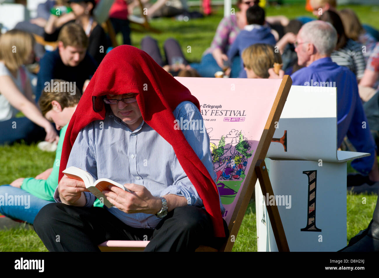 Lesebuch der Mann saß im Liegestuhl in der Sonne mit Kopf bedeckt durch rote Jumper bei Hay Festival 2013 Hay on Wye Powys Wales UK Stockfoto