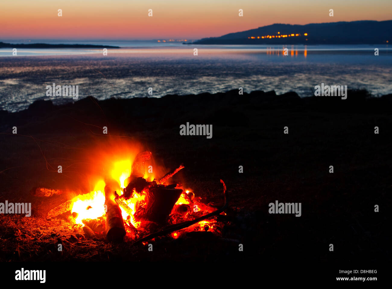 Am Strand mit der Küste und Meer in der Vista gesammelt brüllend Lagerfeuer aus Echtholz Stockfoto