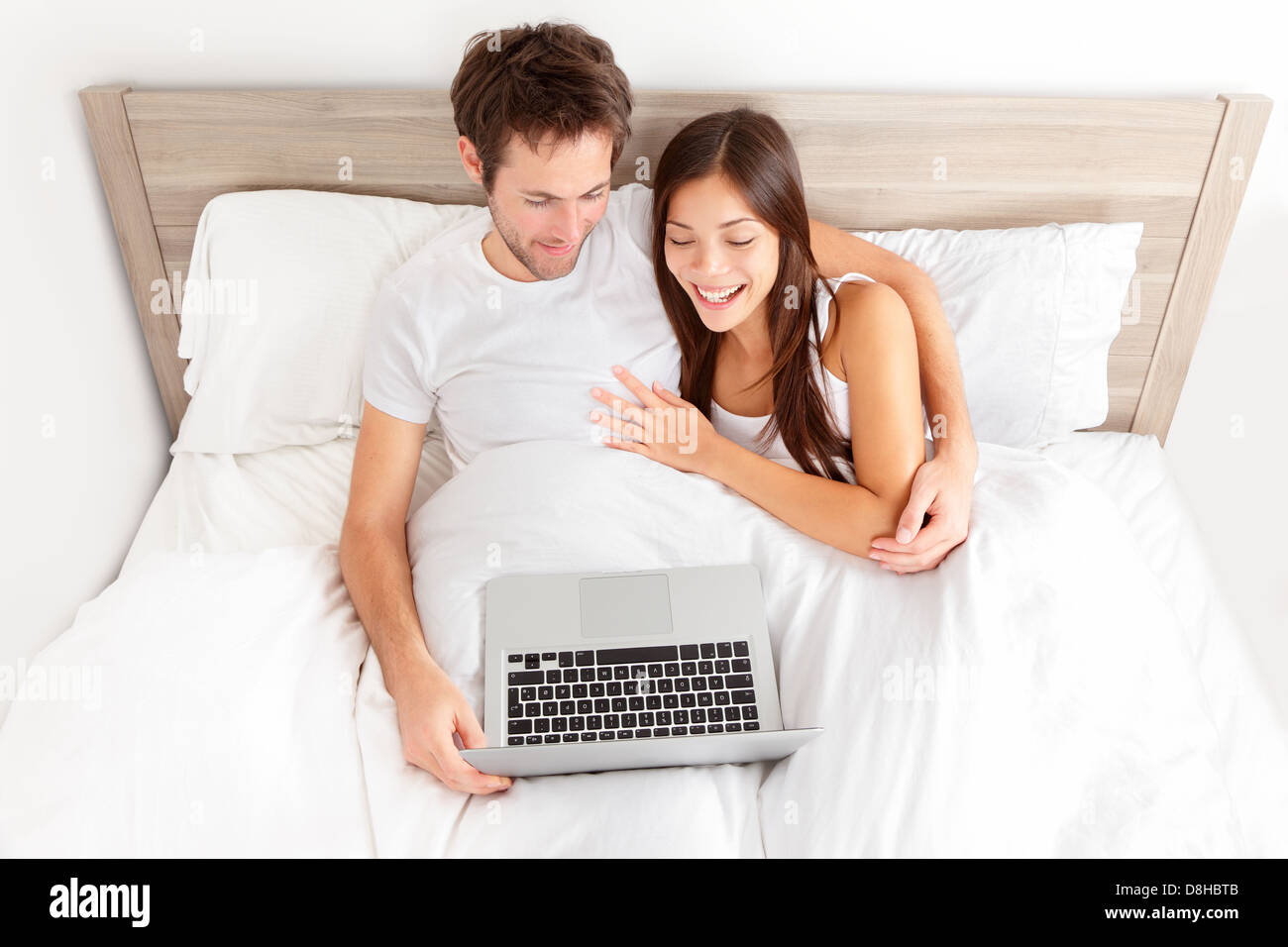 Junges Paar entspannende im Bett. Gerne zärtlich junges Paar entspannende im Bett genießen, sich lachend in der Unterhaltung mit Ihrem Laptop. Stockfoto