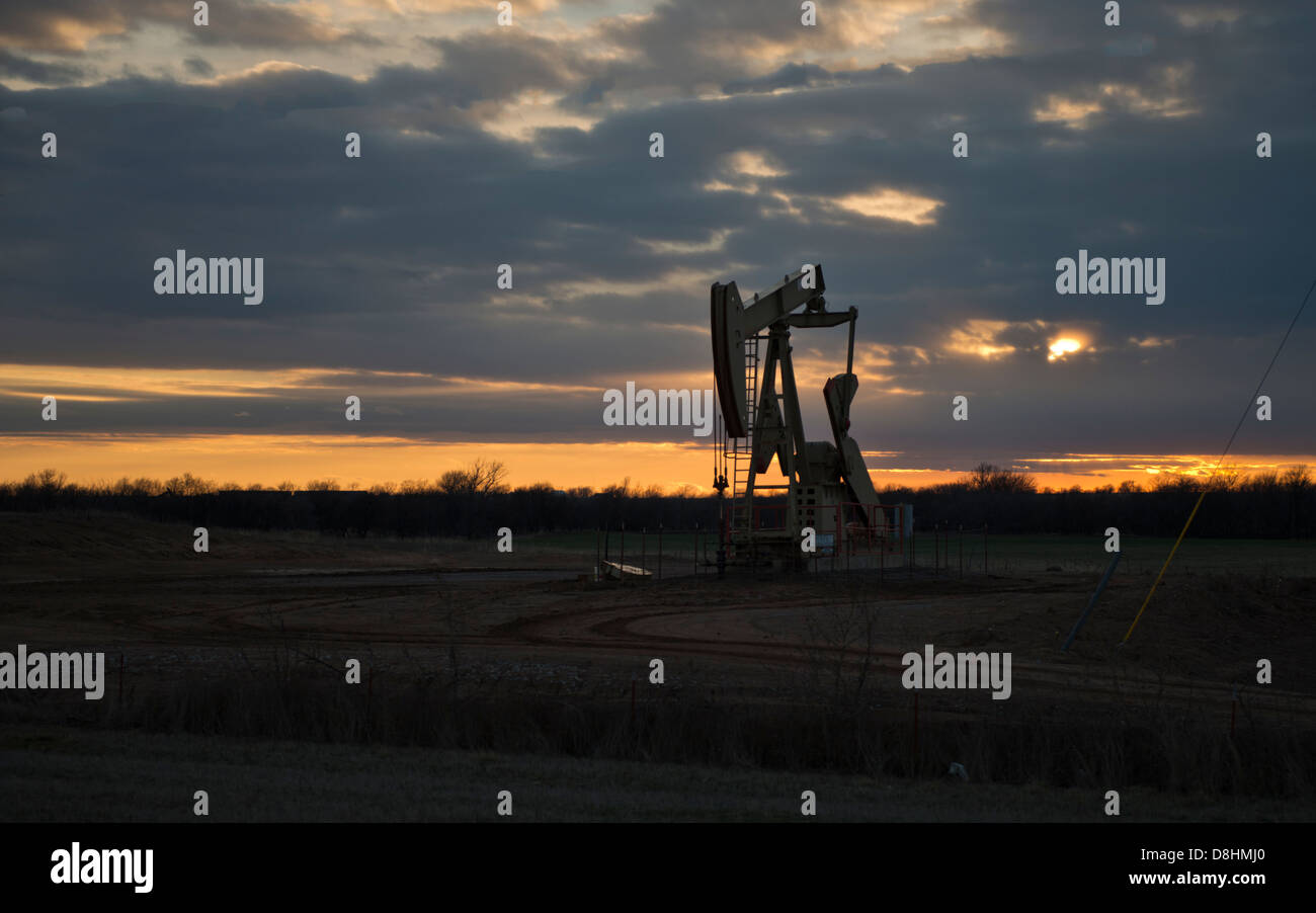 Eine Pumpe Jack Pumpenöl aus einer gut Silhouette gegen einen Sonnenuntergang in Kansas, USA, Vereinigte Staaten. Stockfoto
