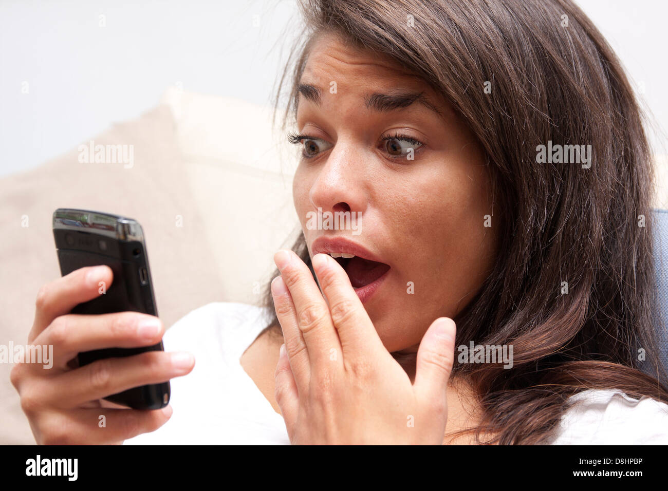 junge Frau mit Ausdruck der Schock Blick auf ihr i-phone Stockfoto