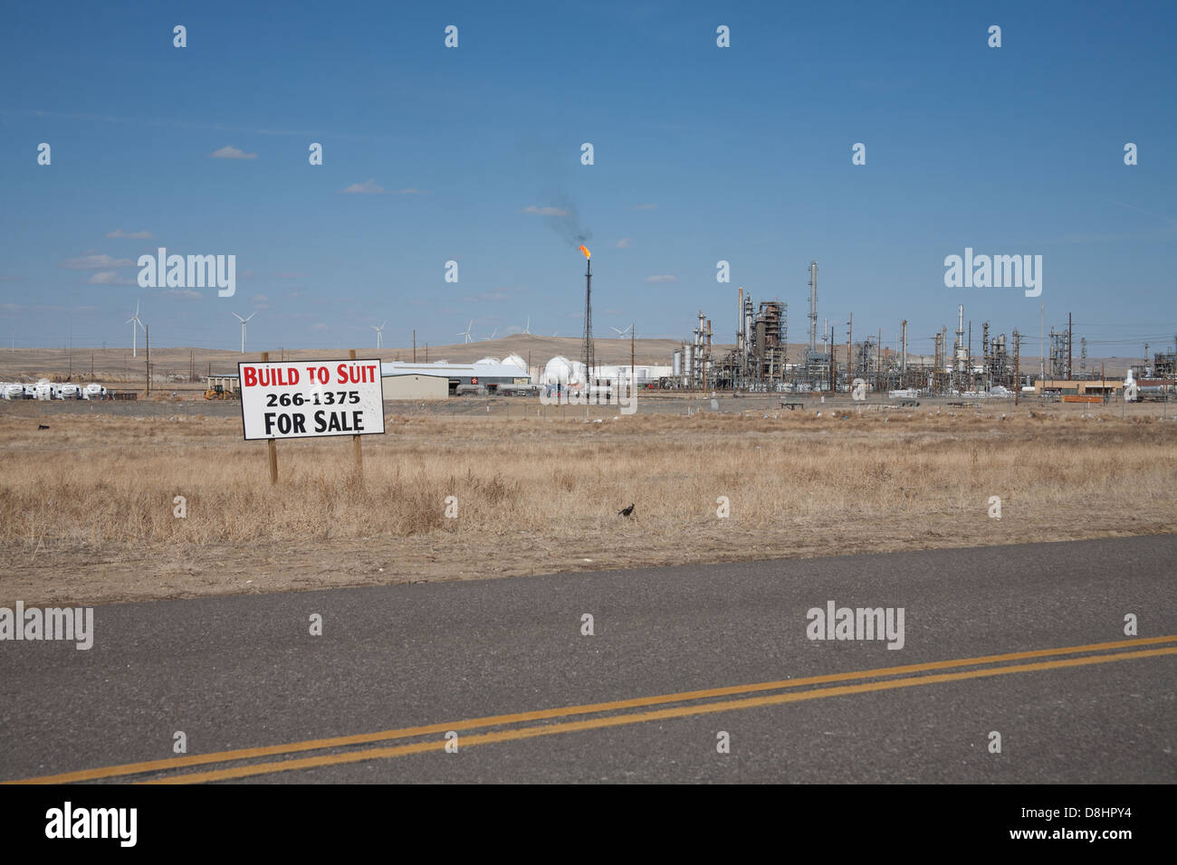 Ironisch Energie Foto mit Windmühlen im Hintergrund und eine Öl-Raffinerie und Gas flare im Vordergrund. Stockfoto