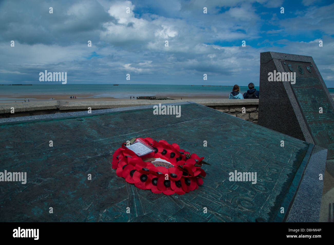 Arromanches, Normandie, Frankreich. Blumen aus Papier auf ein Denkmal die "Maulbeere" künstlichen Hafens, die für die Invasion verwendet wurde. Stockfoto