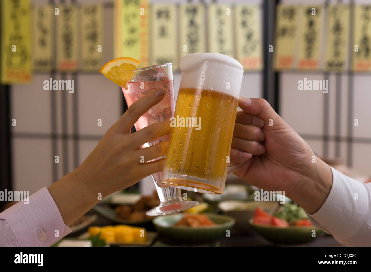 Zwei Menschen, die mit Bier und Cocktail in Izakaya rösten Stockfoto