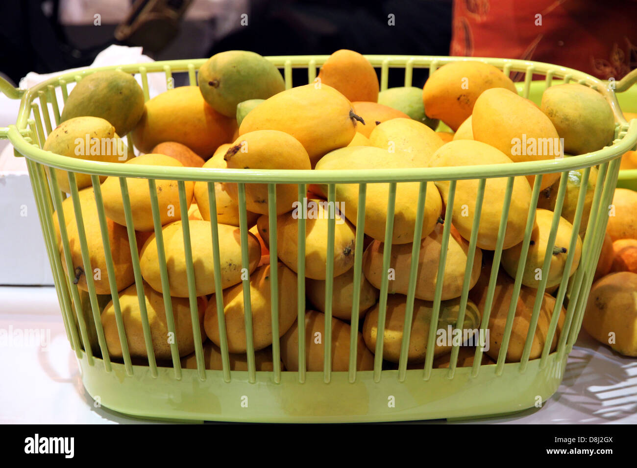 Eine Reife Mango in den grünen Korb legen sie eine gelbe Farbe. Stockfoto