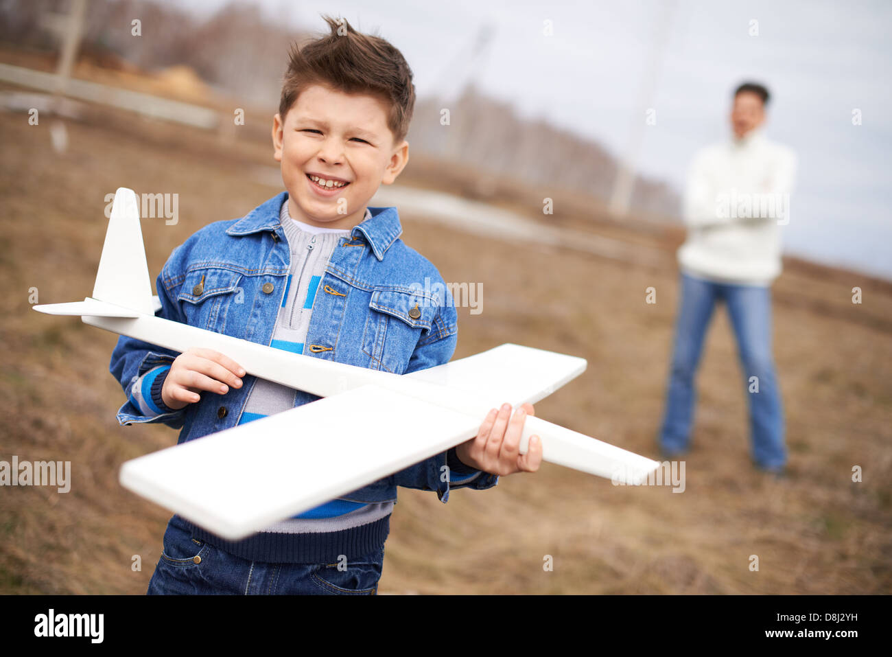 Foto von glückliches Kind mit Blick in die Kamera mit seinem Vater auf Hintergrund Spielzeugflugzeug Stockfoto