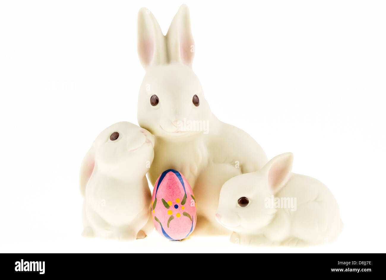 Keramik-Hase-Trio mit ein Easter Egg auf dem weißen Hintergrund isoliert. Stockfoto