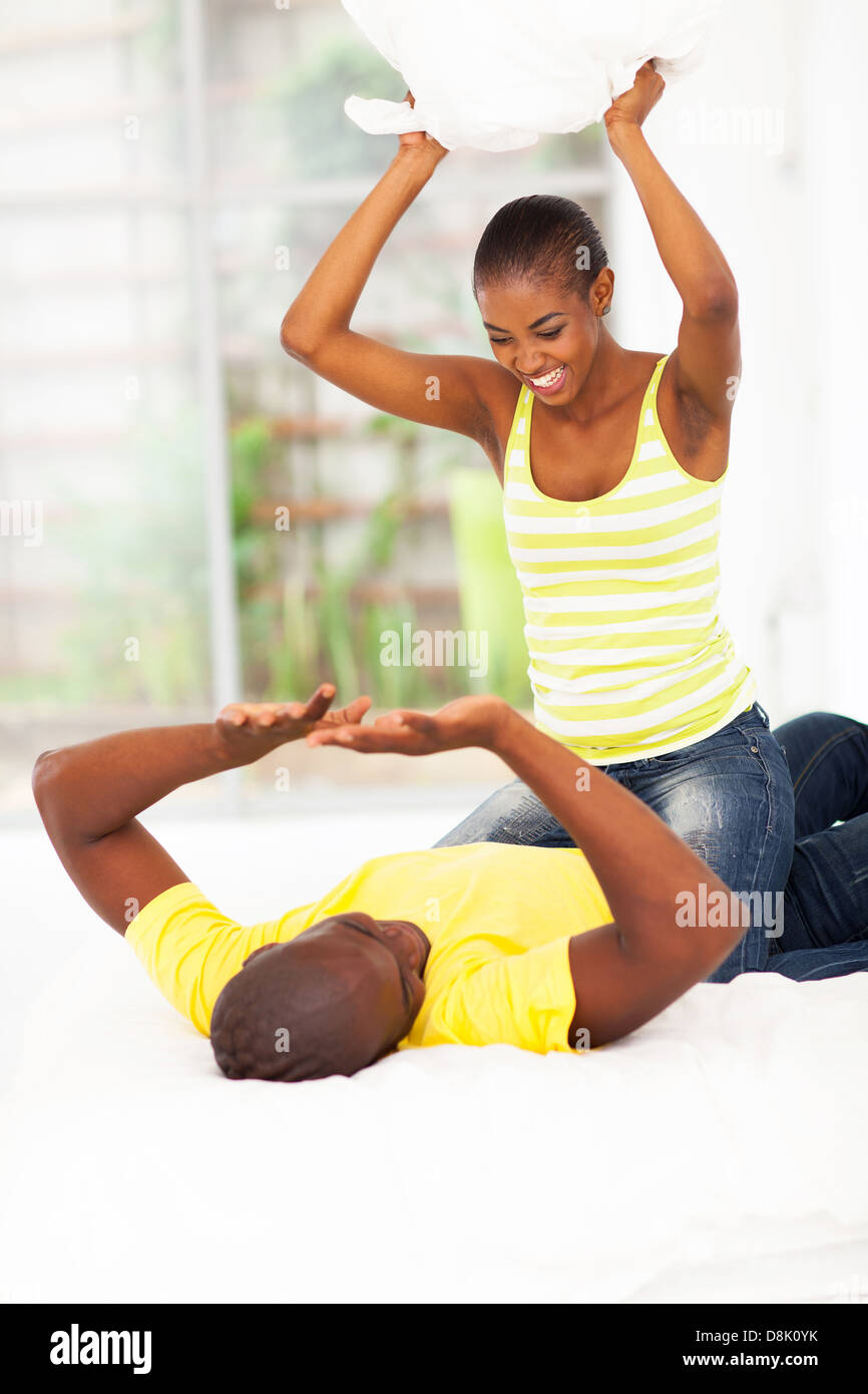 verspielte junge afrikanische paar Kissenschlacht im Schlafzimmer Stockfoto