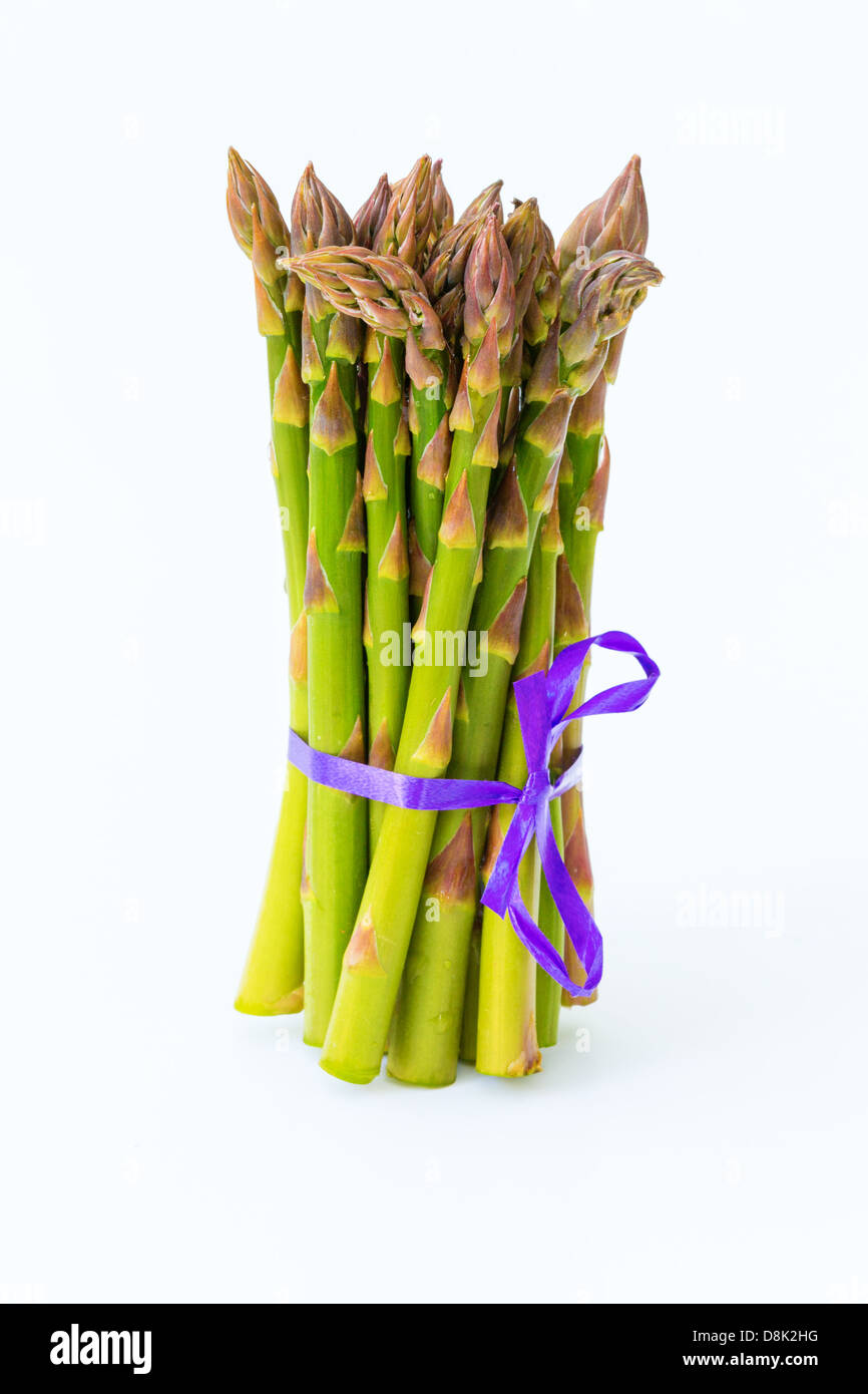 Reihe von Spargel auf weißem Hintergrund mit lila Band Stockfoto