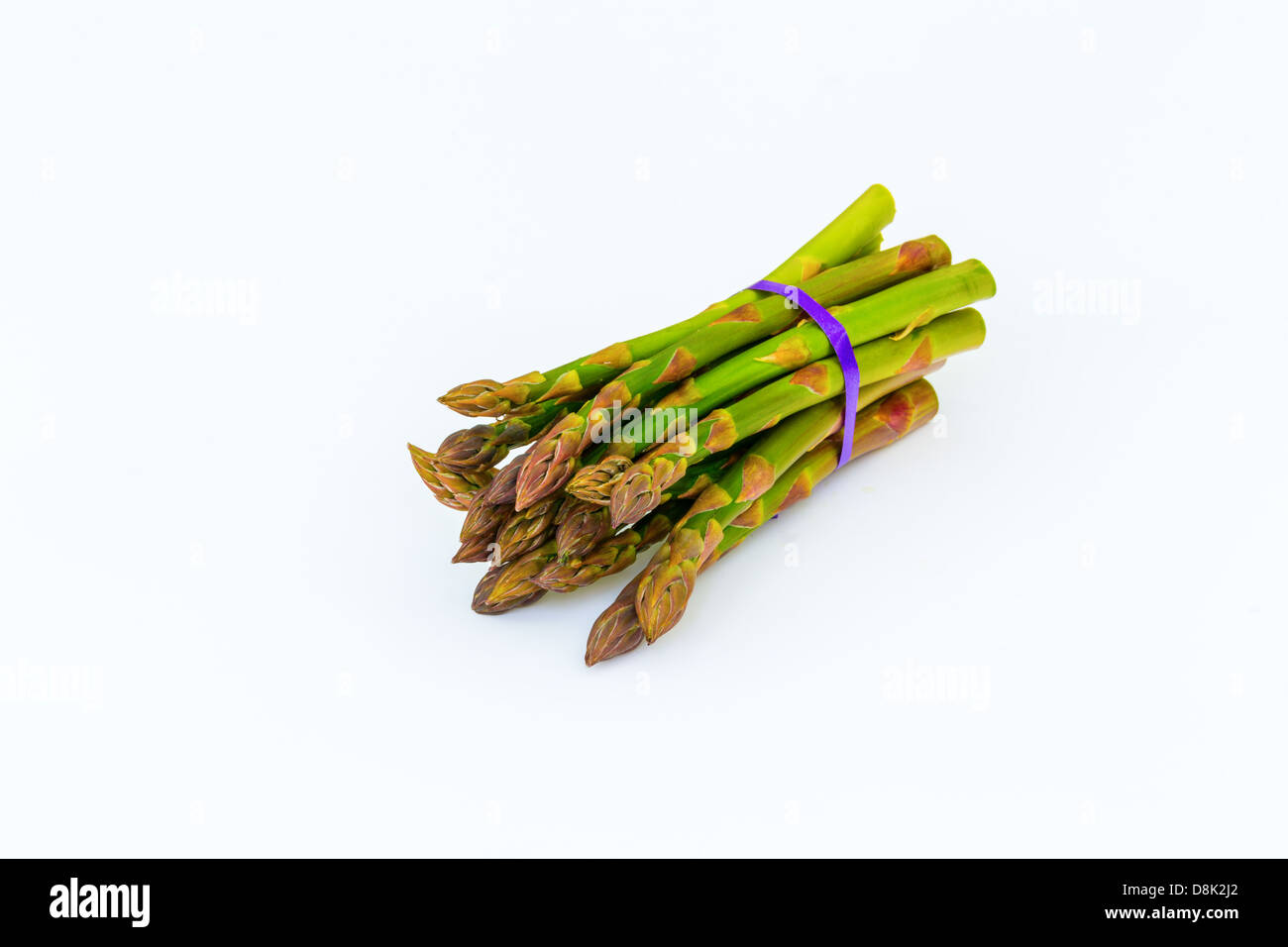 Reihe von Spargel auf weißem Hintergrund mit lila Band Stockfoto