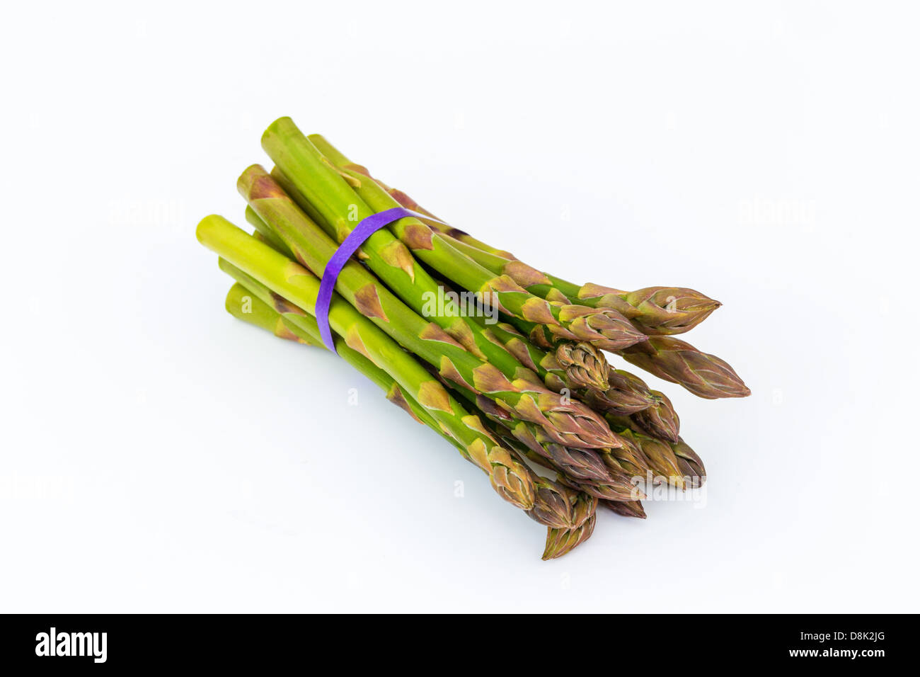 Reihe von Spargel auf weißem Hintergrund mit lila Band Stockfoto